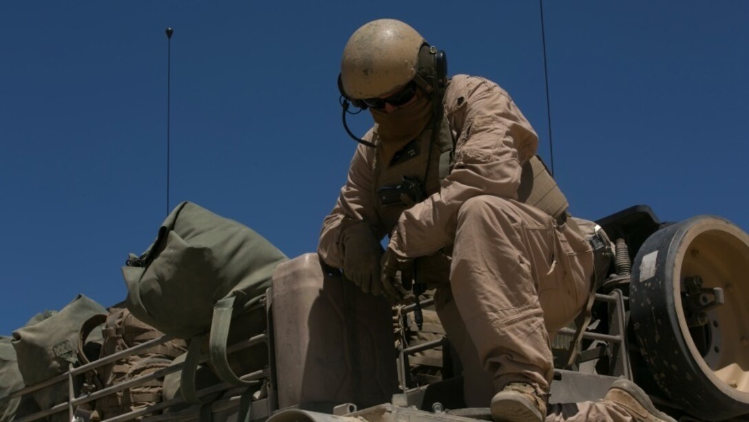 Sgt. Justin Cope, tank commander, Company A, 1st Tank Battalion, examines an M1A1 Abrams Tank’s rear fuel tank at Acorn Training Area, July 16, 2015. Each company within 1st Tanks consists of approximately 14 tanks. (Official Marine Corps photo by Lance Cpl. Thomas Mudd/Released)