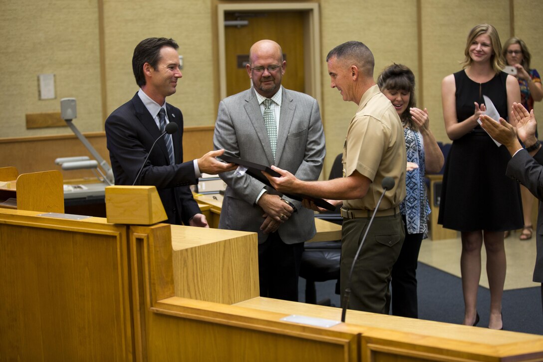 Mark Kersey, San Diego councilman for Fifth District, gives a plaque to Col. John Farnam, commanding officer of Marine Corps Air Station Miramar, at the end of the “Colonel John P. Farnam Day” proclamation at the San Diego City Council, July 28. The city council members also described Farnam’s initiatives during his time at MCAS Miramar, including his conservation efforts on the installation. (U.S. Marine Corps photo by Cpl. Michael Thorn/Released)