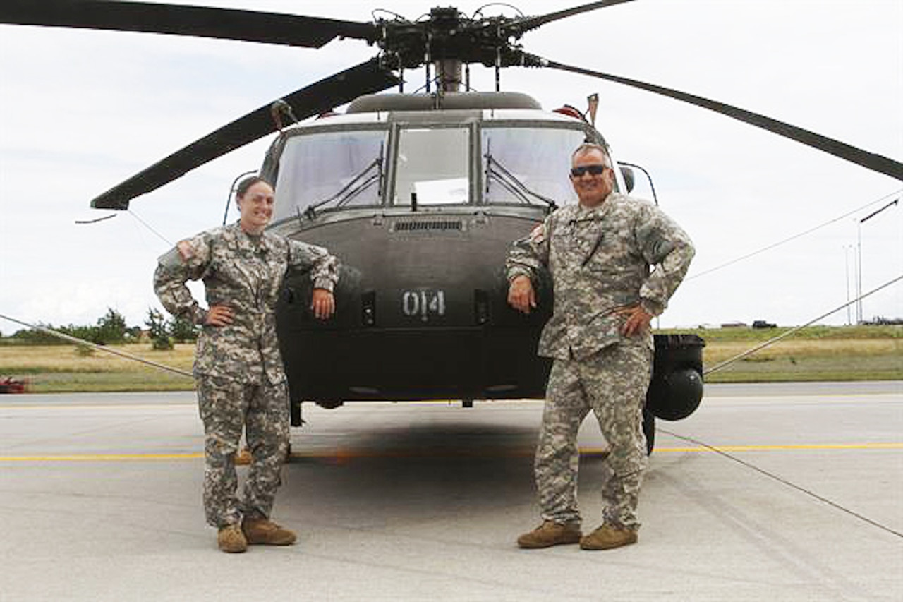 New York Army National Guard members Warrant Officer Meghan Polis, left, and Chief Warrant Officer 3 Stephen Polis -- a daughter and dad flying duo who are both assigned to Company B 3rd Battalion 142nd Assault Helicopter Battalion -- pose in front of a UH-60 Black Hawk helicopter at Fort Drum, New York, July 22, 2015. U.S. Army photo by Sgt. Jonathan Monfiletto