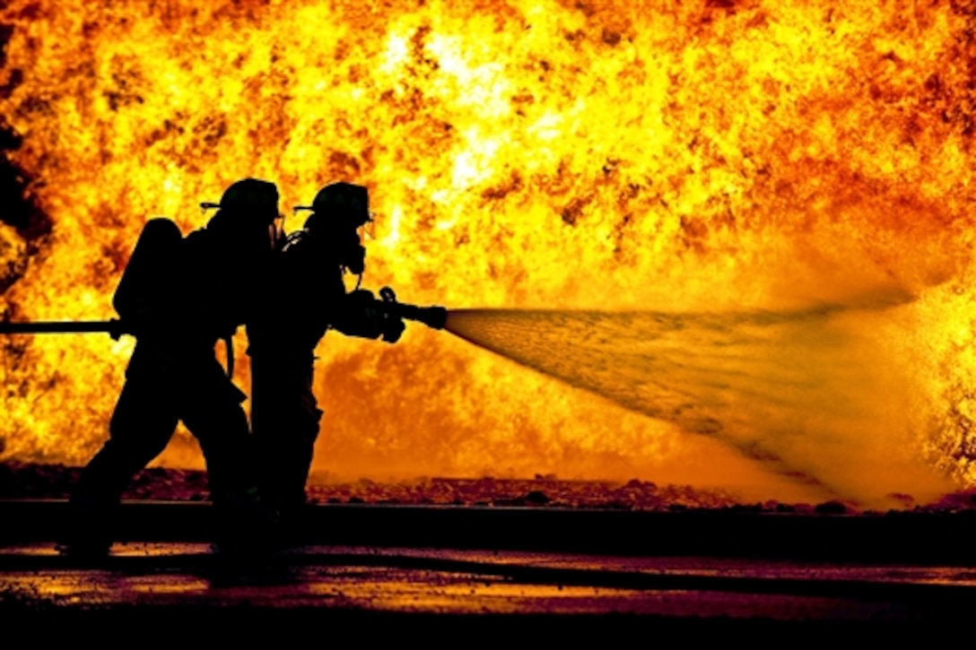 Airmen battle flames from a simulated aircraft fire at the Alpena Combat Readiness Training Center in Alpena County, Mich., July 22, 2015. The airmen are assigned to the Indiana Air National Guard's 122nd Fighter Wing.