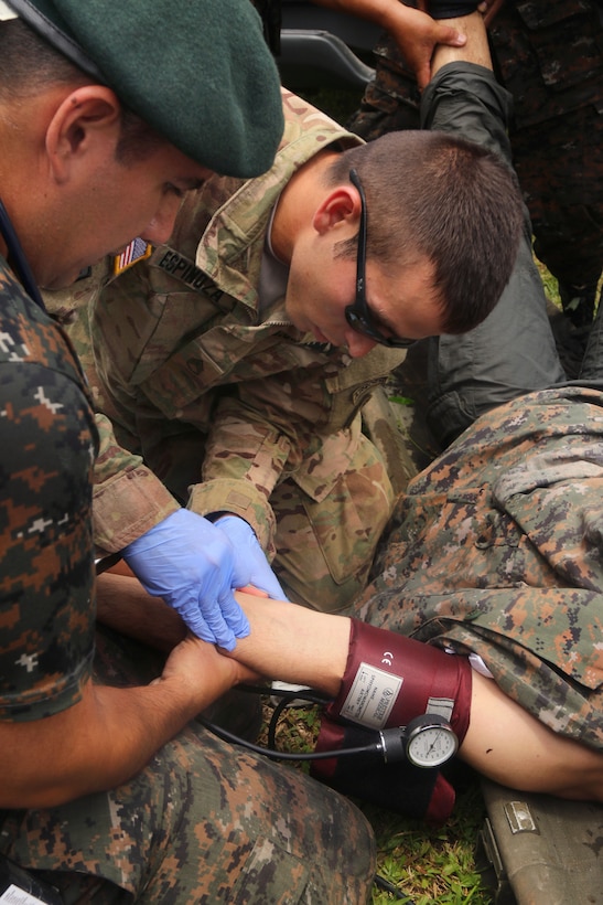 A U.S. soldier, center, and Guatemalan military health care specialists administer an IV line to a heat casualty after the water event portion of the assault team competition during Fuerzas Comando 2015 in Poptun, Guatemala, July 20, 2015. The U.S. soldier is a combat medic. Medical care specialists are on hand throughout the competition to ensure care to all participants.