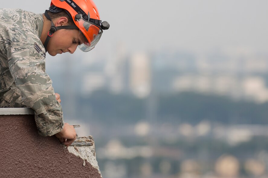 Senior Airman Cory Pepin, 374th Civil Engineer Squadron fire fighter, inspects a building recently struck by lightning at Yokota Air Base, Japan, July 30, 2015. Pepin removed loose debris from the contact point, ensuring no personnel were in risk of harm and no property of damage. (U.S. Air Force photo by Osakabe Yasuo/Released)