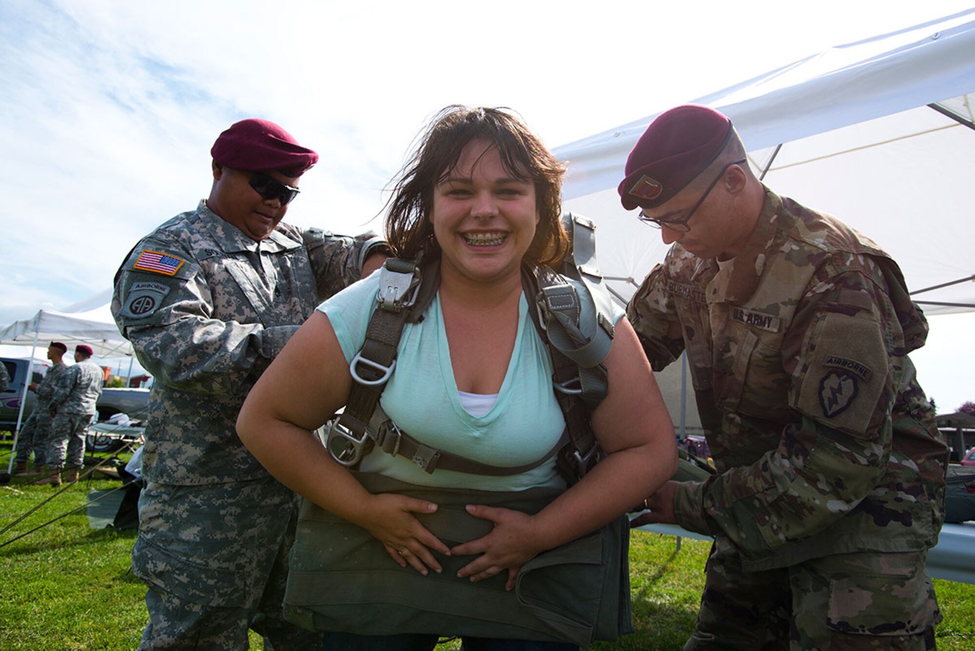 Army Staff Sgt. Dominador Soliven, left, and Cpl. Ed Burmaster, right, strap parachuting equipment onto Judy Jessen during Anchorage’s 2015 Tent City Festival July 25. Soliven and Burmaster are members of 2nd Battalion, 377th Parachute Field Artillery Regiment, 4th Infantry Brigade Combat Team (Airborne). (U.S. Air Force photos/Tech. Sgt. Robert Barnett)