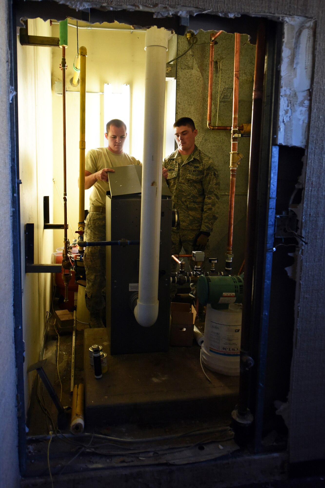 Senior Airman Julian Donahue and Airman 1st Class Joseph Konecny, 341st Civil Engineer Squadron Heating Ventilation and Air Conditioning technicians, take the top cover off of a boiler to access the main control board July 30, 2015, at Malmstrom Air Force Base, Mont. HVAC completed 102 job orders for the month of July. (U.S. Air Force photo/Chris Willis)