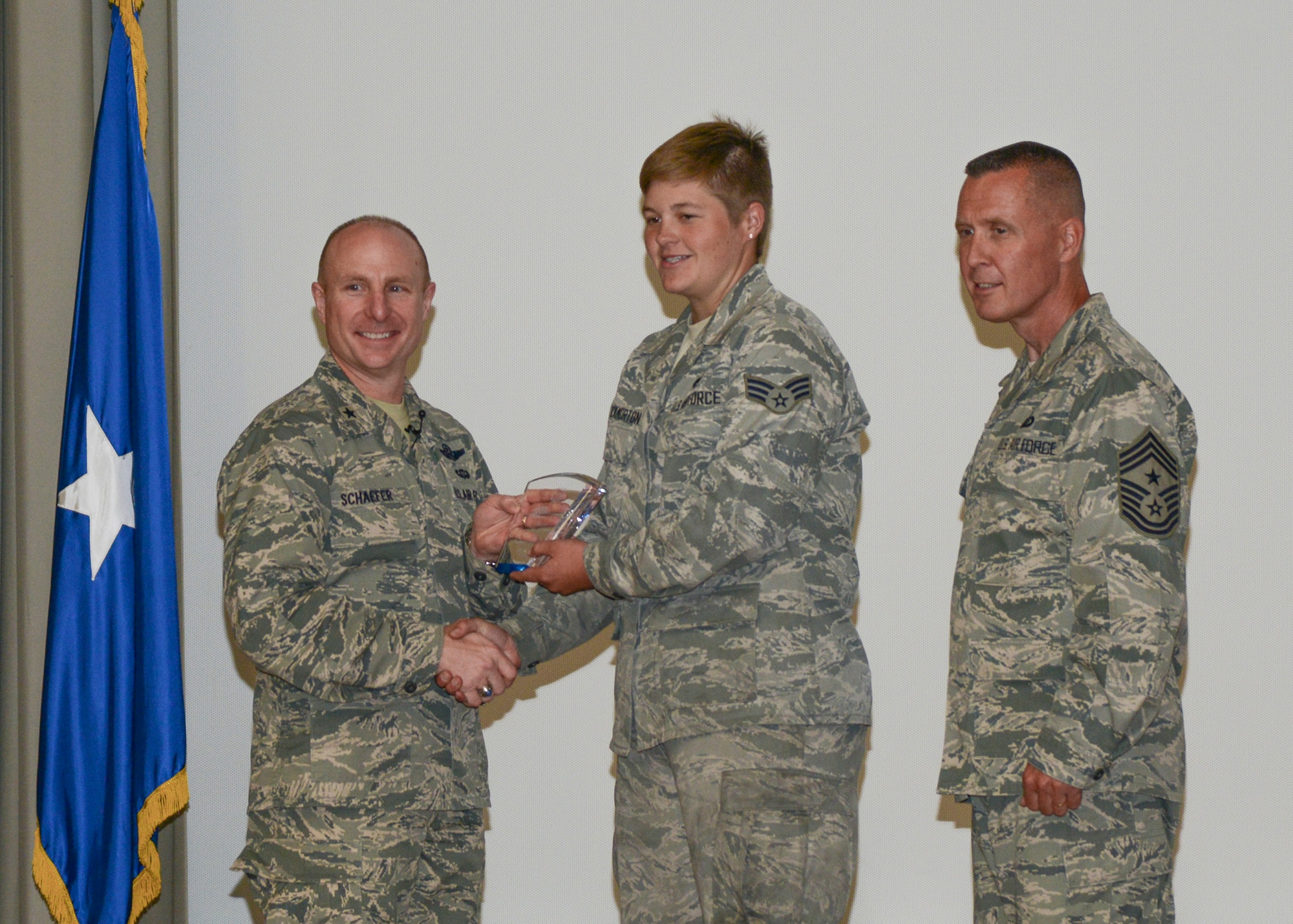 Senior Airman Shelbey Throckmorton, 412th Maintenance Group, receives the Dorm of the Quarter award from Brig. Gen. Carl Schaefer, 412th Test Wing commander. Chief Master Sgt. David Smith, 412th TW command chief, was also on stage to congratulate Throckmorton. (U.S. Air Force photo by Rebecca Amber)