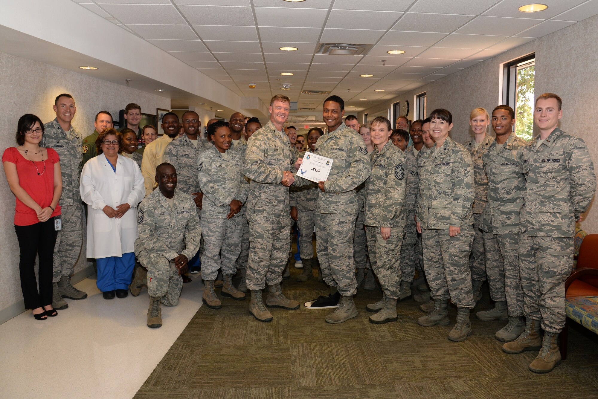 Staff Sgt. Adaultha Lewis, center, 47th Medical Operations Squadron flight medicine NCOIC, poses with Col. Thomas Shank, center-left, 47th Flying Training Wing commander, and Chief Master Sgt. Teresa Clapper, 47th FTW command chief, after accepting the “XLer of the Week” award, here, July 22, 2015. The “XLer” is a weekly award chosen by wing leadership and is presented to those who consistently make outstanding contributions to their unit and Laughlin. (U.S. Air Force photo by Airman 1st Class Brandon May)