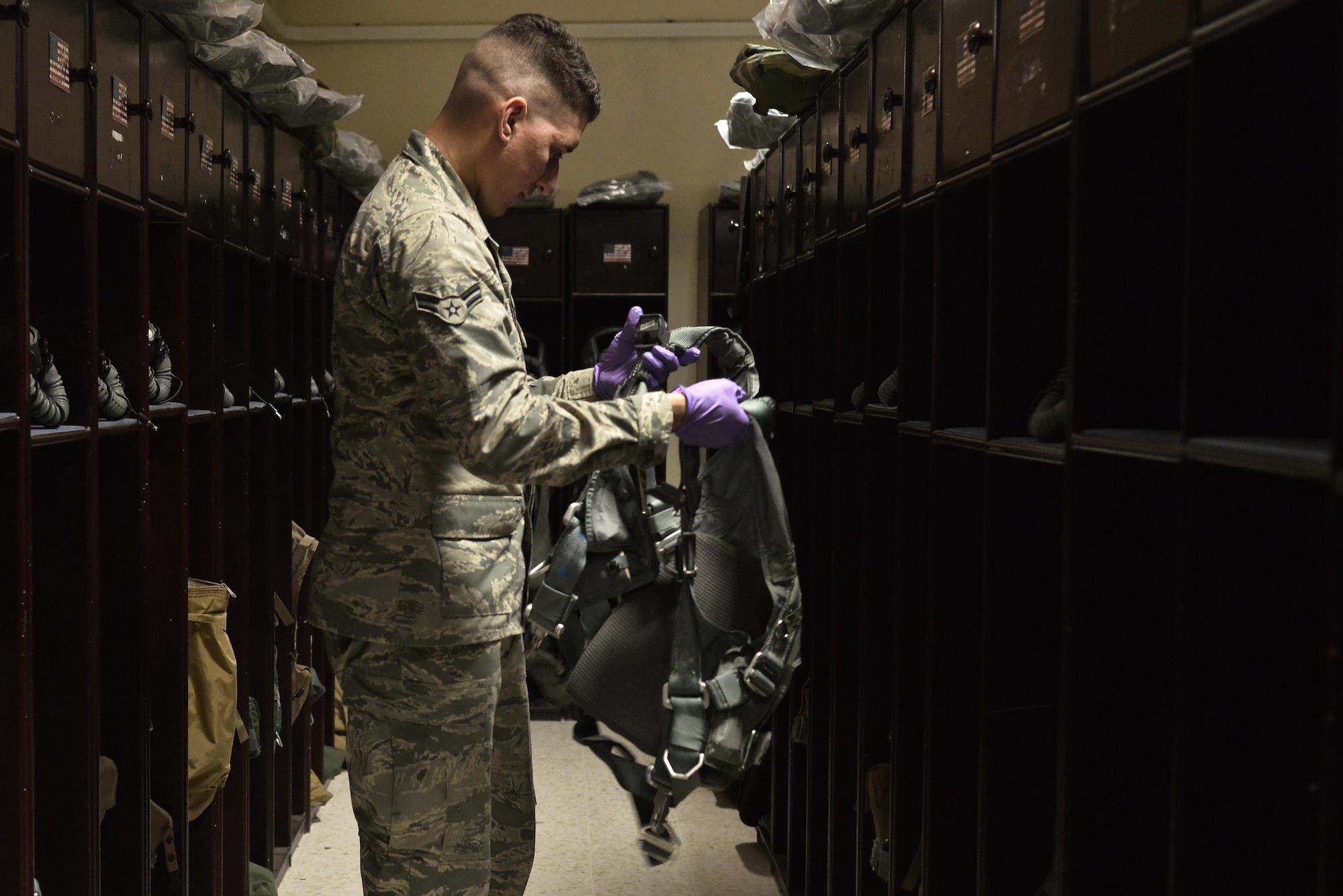 Airman 1st Class Andrew Gonzalez, 379th Expeditionary Operations Support Squadron Aircrew Flight Equipment, checks a harness for loose strings, tabs and tears before making requested adjustments from the aircrew July 29, 2015 at Al Udeid Air Base, Qatar. AFE airmen are responsible for helmet harnesses, life preservers and parachutes. They also ensure aircrew members are properly armed prior to takeoff and clear them after each mission. (U.S. Air Force photo/Staff Sgt. Alexandre Montes)