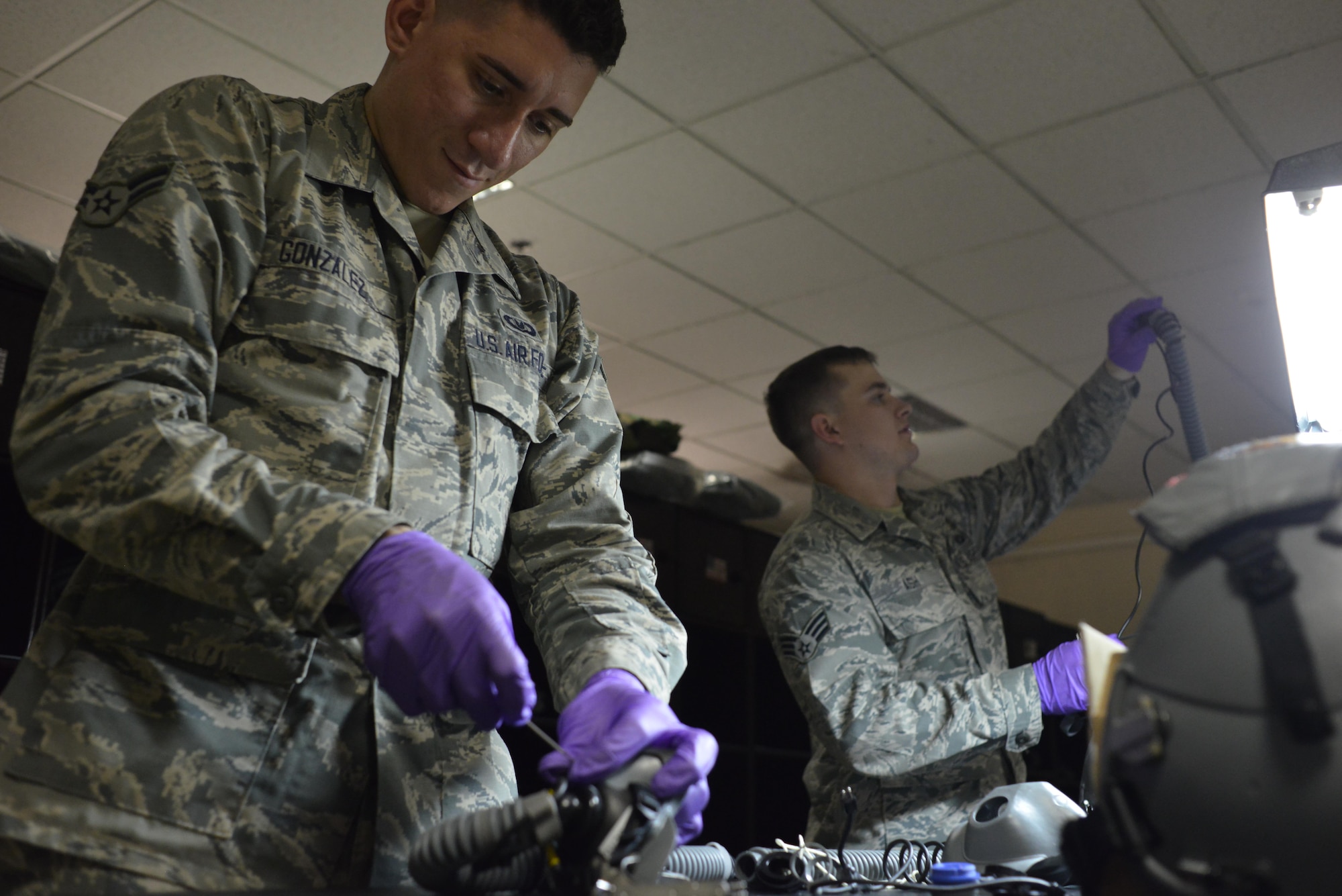 Airman 1st Class Andrew Gonzalez and Senior Airman James Ash, 379th Expeditionary Operations Support Squadron Aircrew Flight Equipment, each disassemble and sanitize aircrew helmets to ensure safety and function of equipment while in flight July 29, 2015 at Al Udeid Air Base, Qatar. Following technical orders allows airmen to adjust, clean and maintain aircrew equipment without fault giving flyers a peace of mind while completing sorties. (U.S. Air Force photo/Staff Sgt. Alexandre Montes) 