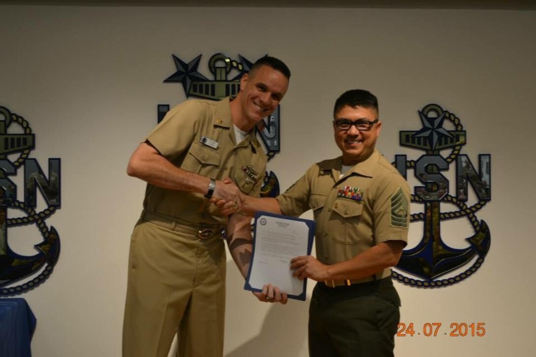 The Director of the Navy Senior Enlisted Academy, Command Master Chief Richard Curtis (AW/IDW/SS/SW) (left), congratulates Master Sgt. William Call, the bandmaster for Marine Corps Band New Orleans, for achieving the highest overall grade point average for Class 188 and as a result being named as the class honor graduate, during the graduation ceremony held in Newport, R.I., July 24, 2015.  Call attributes his success to having outstanding role models such as his father and grandfather who both retired from the Air Force and Army, respectively.