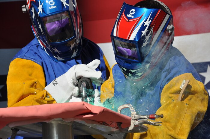 MOBILE, Alabama - The Honorable Robert L. Crowell (left), mayor of Carson City, Nev., welds his initials into the keel plate of JHSV 7 -- the future USNS Carson City -- with the help of Austal USA welder Mr. Tuong Phan during the keel authentication ceremony July 31. JHSVs provide fast intra-theater transportation of troops, military vehicles, equipment and supplies in support of a wide variety of missions.