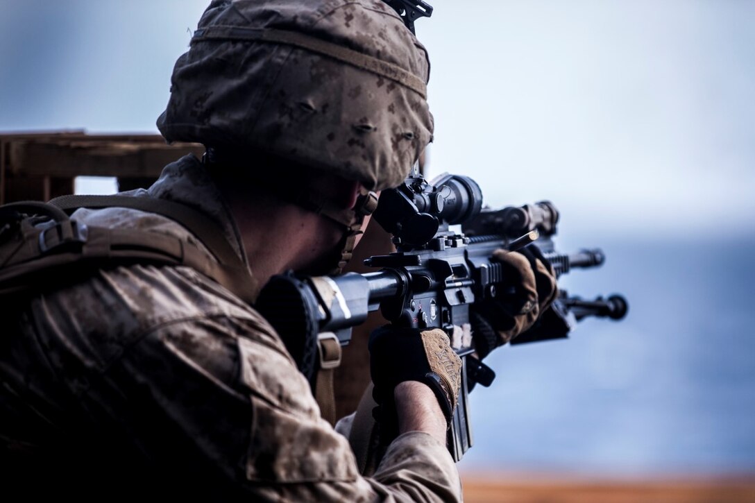 INDIAN OCEAN (July 30, 2015) A U.S. Marine with Lima Company, Battalion Landing Team 3rd Battalion, 1st Marine Regiment, 15th Marine Expeditionary Unit, fires his weapon during a deck shoot aboard the amphibious assault ship USS Essex (LHD 2). The Marines practiced shooting from behind a barricade to simulate staying behind cover during a fire fight. The 15th MEU is embarked on the Essex Amphibious Ready Group and deployed to maintain regional security in the U.S. 5th Fleet area of operations. (U.S. Marine Corps photo by Cpl. Elize McKelvey/Released)