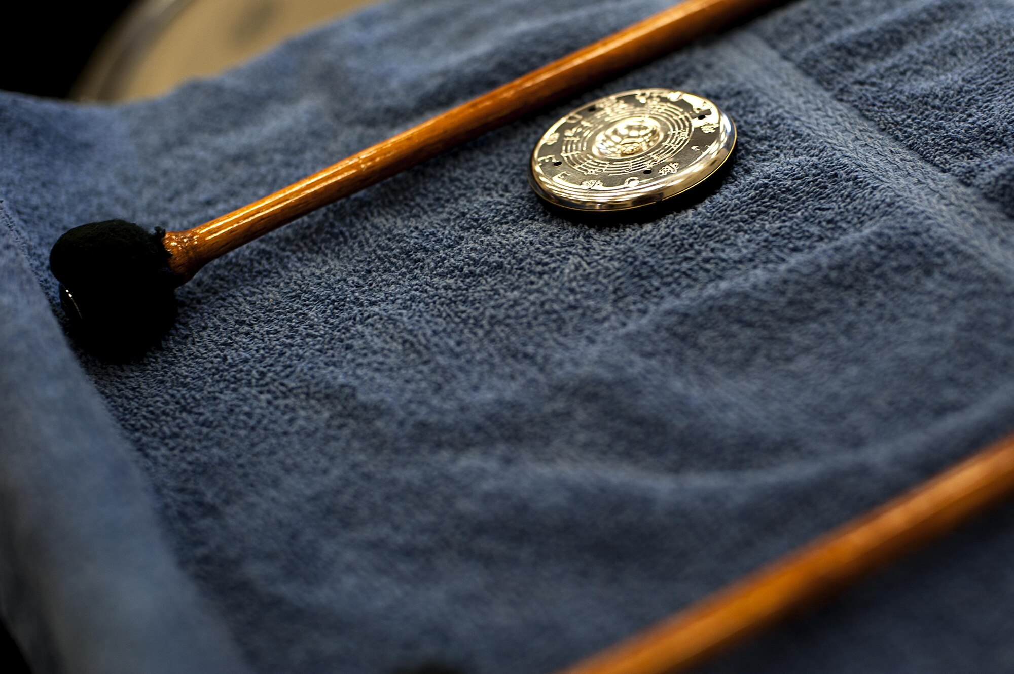 A tuner lies between two drum mallets during band practice in the band hall at Angelo State University, San Angelo, Texas, July 28, 2015. The drummer uses the tuner to keep his drums pitched with the other instruments. (U.S. Air Force photo by Senior Airman Scott Jackson/Released)