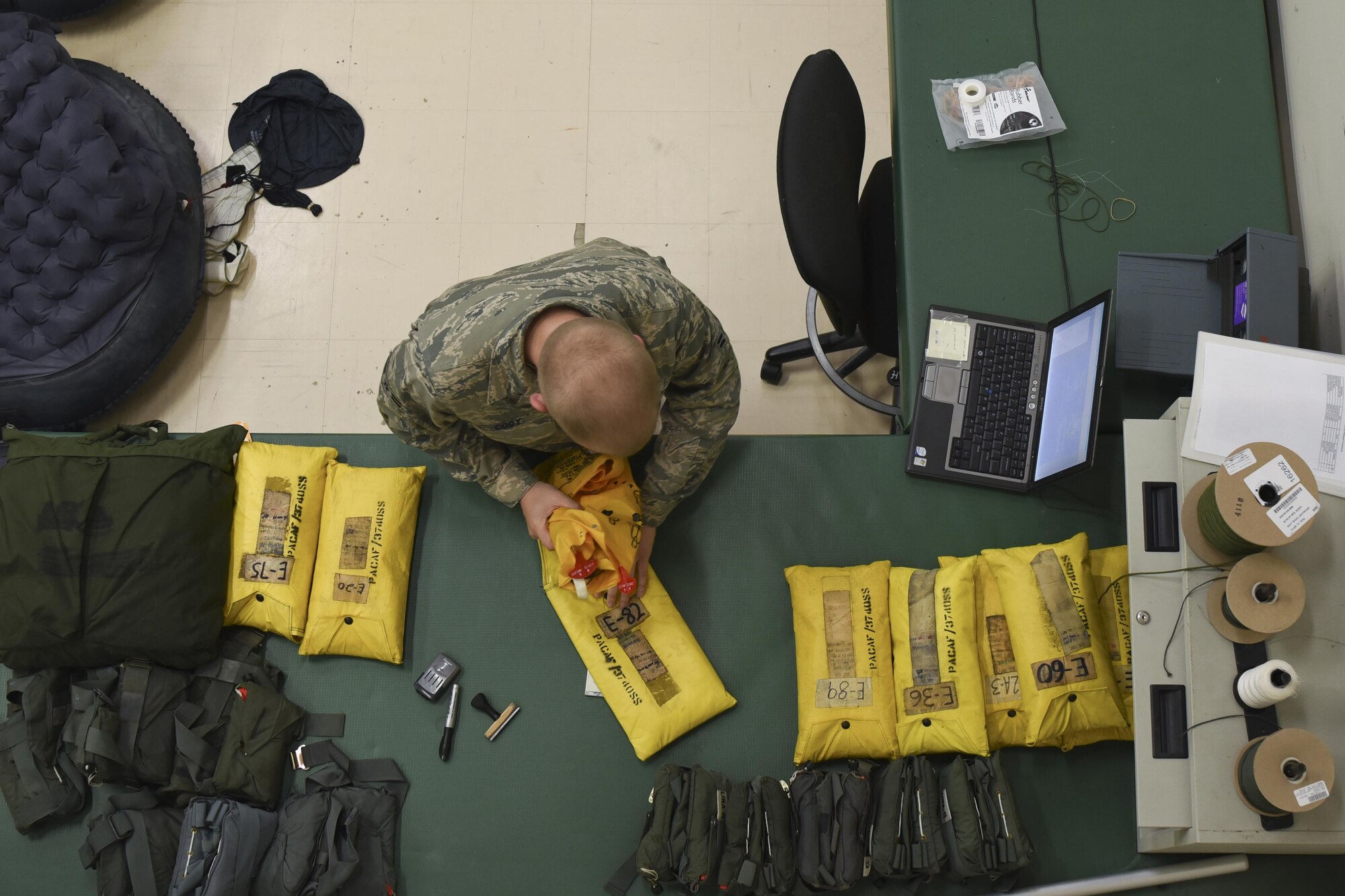 U.S. Air Force Airman 1st Class Zachary Cody, 374th Operations Support Squadron journeyman, inspects a personal floatation device at Yokota Air Base, Japan, July 29, 2015. Cody works on a variety of floatation devices including life preservers for adults, children and infants, as well as full-body individual life rafts. (U.S. Air Force photo by Senior Airman Michael Washburn/Released)