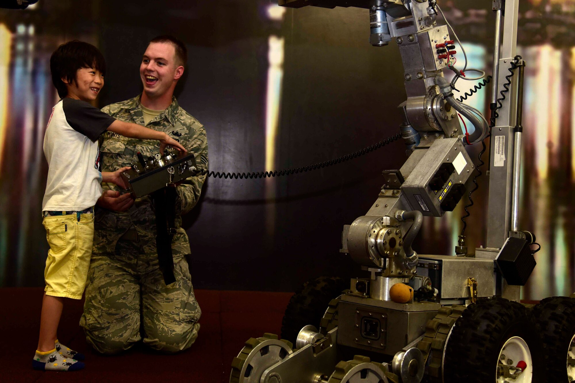 U.S. Air Force Senior Airman Brent Points, 35th Civil Engineer Squadron explosive ordnance disposal technician, shows a child from the Shichinohe Children’s Home how to operate an F-6A Robot at Misawa Air Base, Japan, July 25, 2015. Members of EOD, Misawa's munitions flight and U.S. Naval Air Facility Misawa security forces took part in the "Kids of Ammo" event. (U.S. Air Force photo by Airman 1st Class Jordyn Fetter/Released) 