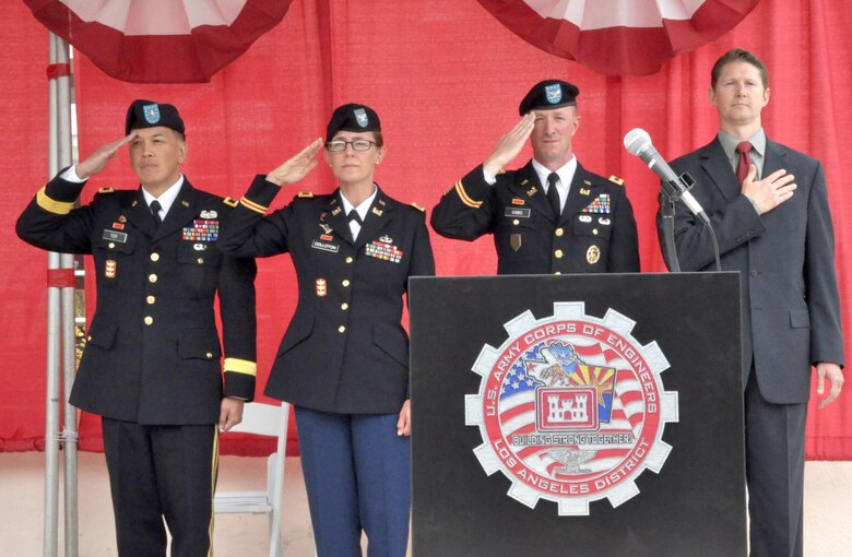 Brig. Gen. Mark Toy, commander of the Corps’ South Pacific Division; Col. Kim Colloton, 60th Commander of the LA District; Col. Kirk Gibbs, 61st Commander of the LA District and David Van Dorpe, Deputy Engineer of the LA District salute the American Flag while the National Anthem singing by being sung by Dawn Parker of the District's Planning Division during a formal change of command ceremony held July 31 at the Community Center at Fort Mac Arthur in San Pedro, Calif.