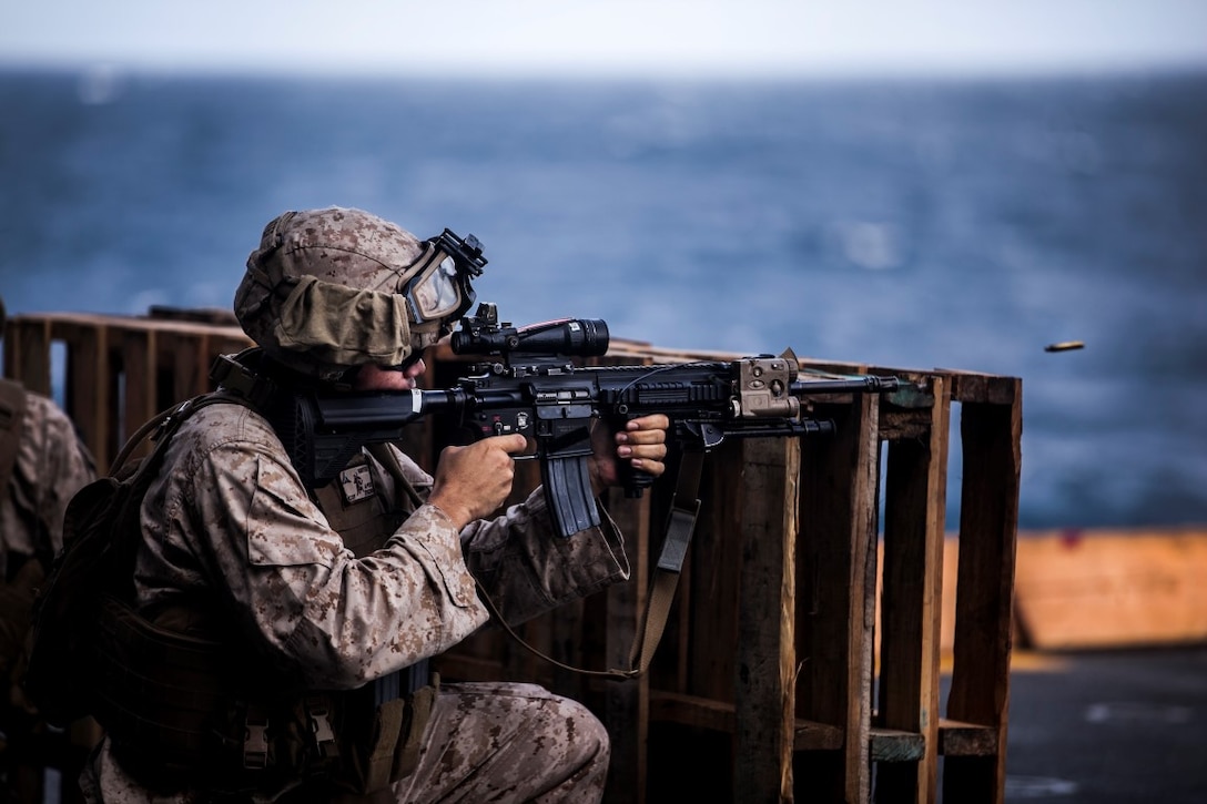 INDIAN OCEAN (July 30, 2015) A U.S. Marine with Lima Company, Battalion Landing Team 3rd Battalion, 1st Marine Regiment, 15th Marine Expeditionary Unit, engages his target during a deck shoot aboard the amphibious assault ship USS Essex (LHD 2). The Marines practiced shooting form behind a barricade to simulate staying behind cover during a fire fight. The 15th MEU is embarked on the Essex Amphibious Ready Group and deployed to maintain regional security in the U.S. 5th Fleet area of operations. (U.S. Marine Corps photo by Cpl. Elize McKelvey /Released)