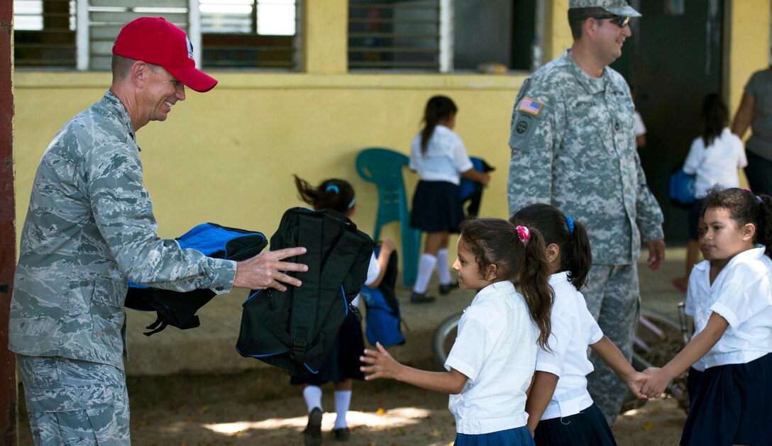 U.S. Air Force Lt. Col. Ryan Elliott provides donated backpacks to students during New Horizons Honduras 2015 at a school in Brisas del Mar, Honduras, July 21, 2015. Elliott commands the 823rd Red Horse Squadron and the New Horizons Honduras exercise.