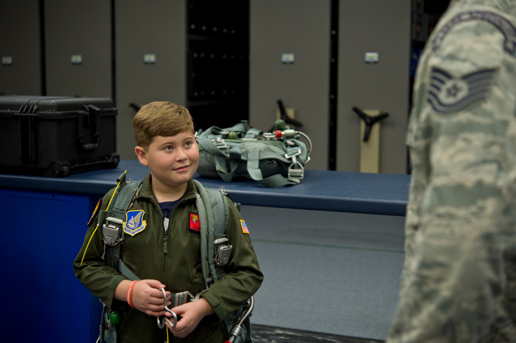 Eddie Paul, a 9-year-old battling Acute Lymphoblastic Leukemia, learns more about Survival, Evasion, Resistance and Escape from SERE Specialist Tech. Sgt. Jeffrey Ray at Joint Base Pearl Harbor-Hickam, Hawaii, July 30, 2015. Eddie Paul spent the day being welcomed into the 535th Airlift Squadron as a Pilot For A Day. (U.S. Air Force photo by 2nd Lt. Kaitlin Daddona/Released)