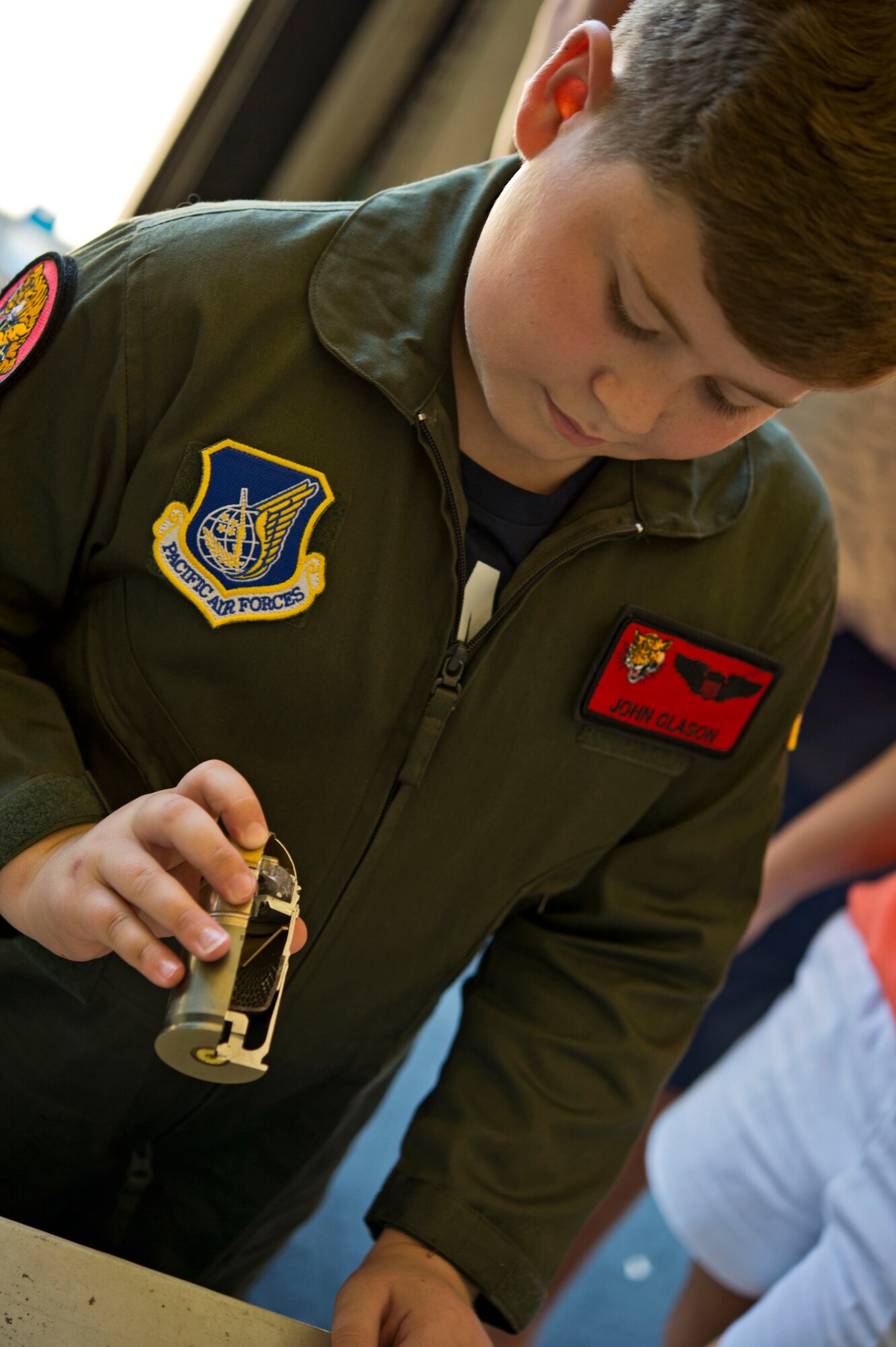 Eddie Paul Bearb wears the wings of Capt. John Clason, a pilot at the 535th Airlift Squadron, as he examines explosives at the EOD squadron at Joint Base Pearl Harbor-Hickam, Hawaii, July 30, 2015. Eddie Paul was a participant of Pilot For A Day, a program created to provide children with serious or chronic conditions the opportunity to experience life as an honorary pilot. He earned his own Wings at the end of the day.  (U.S. Air Force photo by 2nd Lt. Kaitlin Daddona/Released)