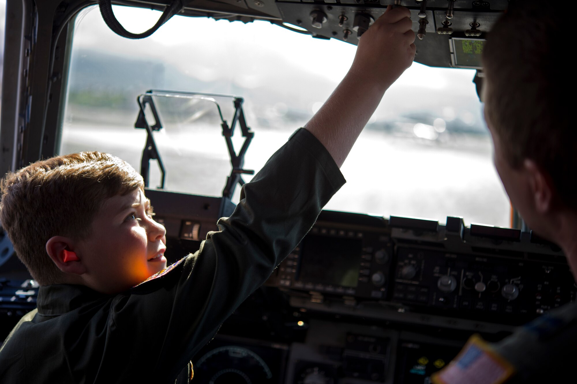 Pilot For A Day Eddie Paul Bearb runs through his pre-flight checklist with Capt. Patrick Dixon in the cockpit of a C-17 at Joint Base Pearl Harbor-Hickam, Hawaii, July 30, 2015. The 9-year-old battling Acute Lymphoblastic Leukemia enjoyed a day living life as a 15th Wing 535th Airlift Squadron member as part of his Dreams Come True wish. (U.S. Air Force photo by 2nd Lt. Kaitlin Daddona/Released)