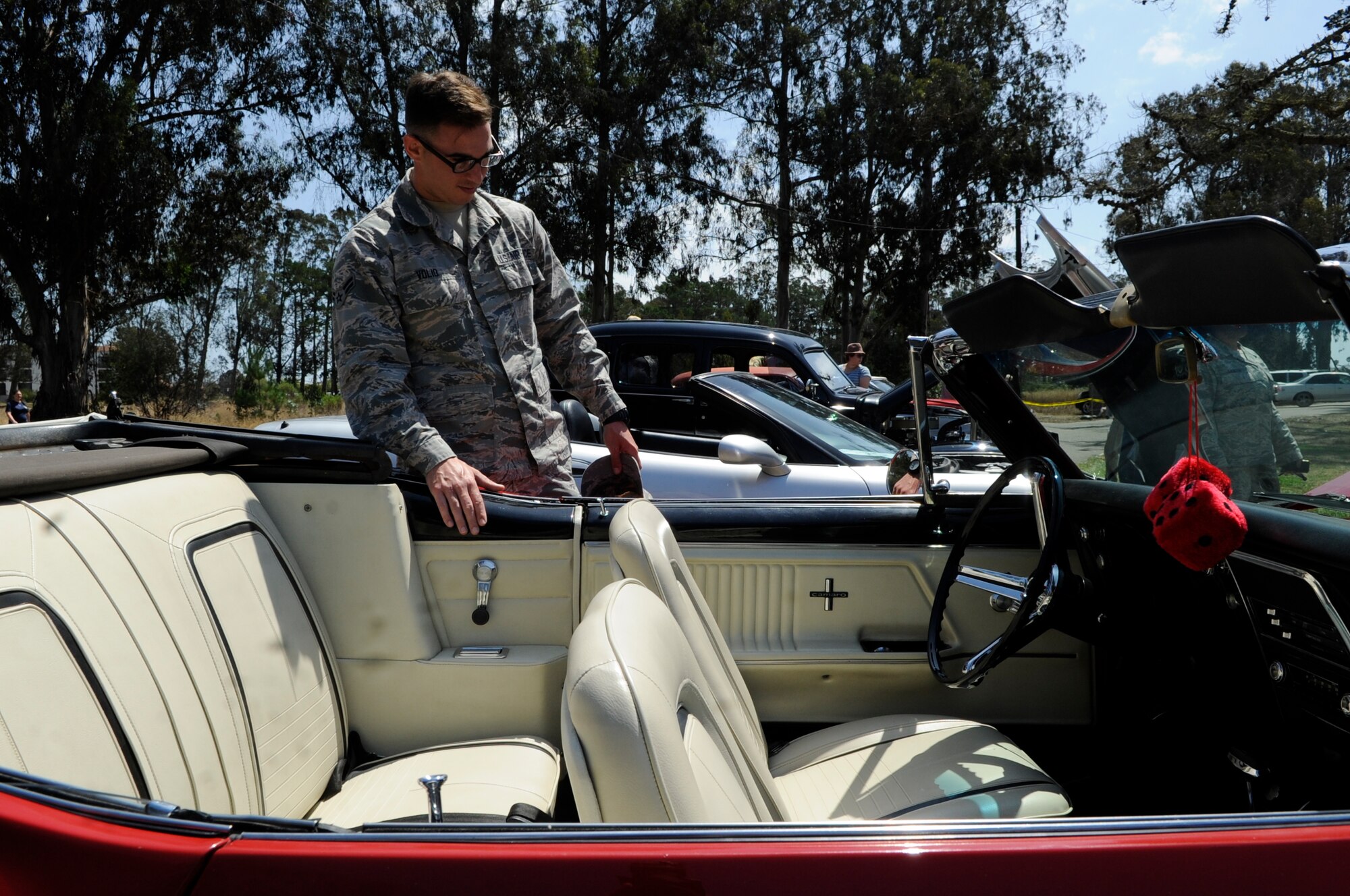 Airman 1st Class Robert Volio, 30th Space Wing Public Affairs photojournalist, admires a classic car during a car show at the 27th annual Texas Blowout event, July 31, 2015, Vandenberg Air Force Base, Calif. The family friendly event featured a barbeque, car show, children’s games and other activities that encouraged base members to relax and build camaraderie, all in preparation for Operation Kids Christmas – an annual event which supports hundreds of underprivileged children from surrounding communities. (U.S. Air Force photo by Senior Airman Shane Phipps/Released)