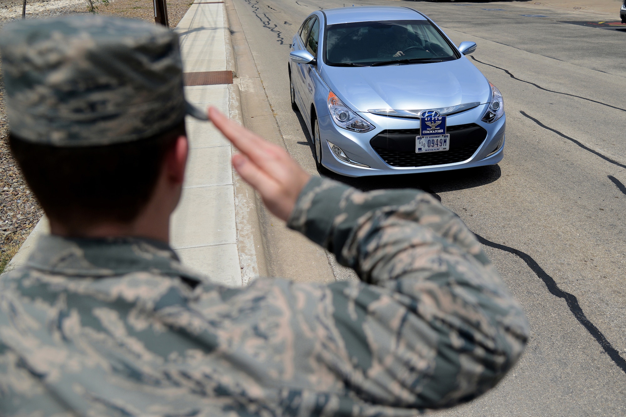 A uniformed military member renders a proper salute as the 47th Flying Training Wing commander's staff vehicle drives by on Laughlin Air Force Base, Texas, July 31, 2015. When on foot, military members are required to salute when a properly marked staff car passes. (U.S. Air Force photo by Airman 1st Class Ariel D. Partlow)(Released)