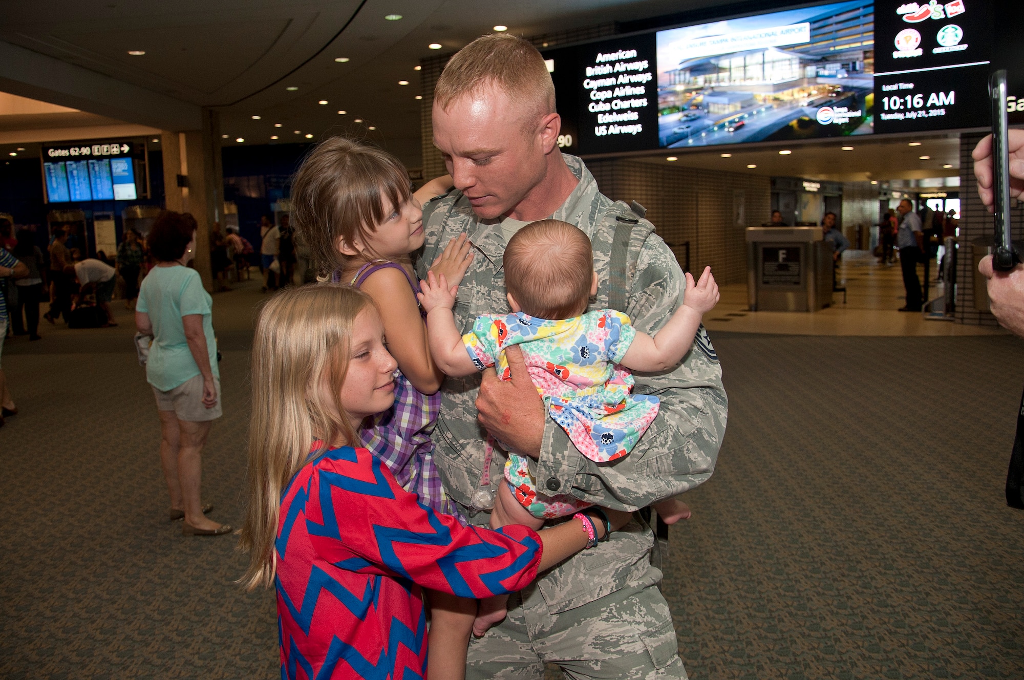 Tech. Sgt. Shannon Hutto, 6th Security Forces Squadron patrolman, hugs and holds his daughter after returning from deployment, July 21, 2015 at the Tampa International Airport in Tampa, Fla. Hutto just arrived from a 6-month deployment in Kuwait where he was able to see his third daughter’s birth via FaceTime. (U.S. Air Force photo by Senior Airman Jenay Randolph/Released)