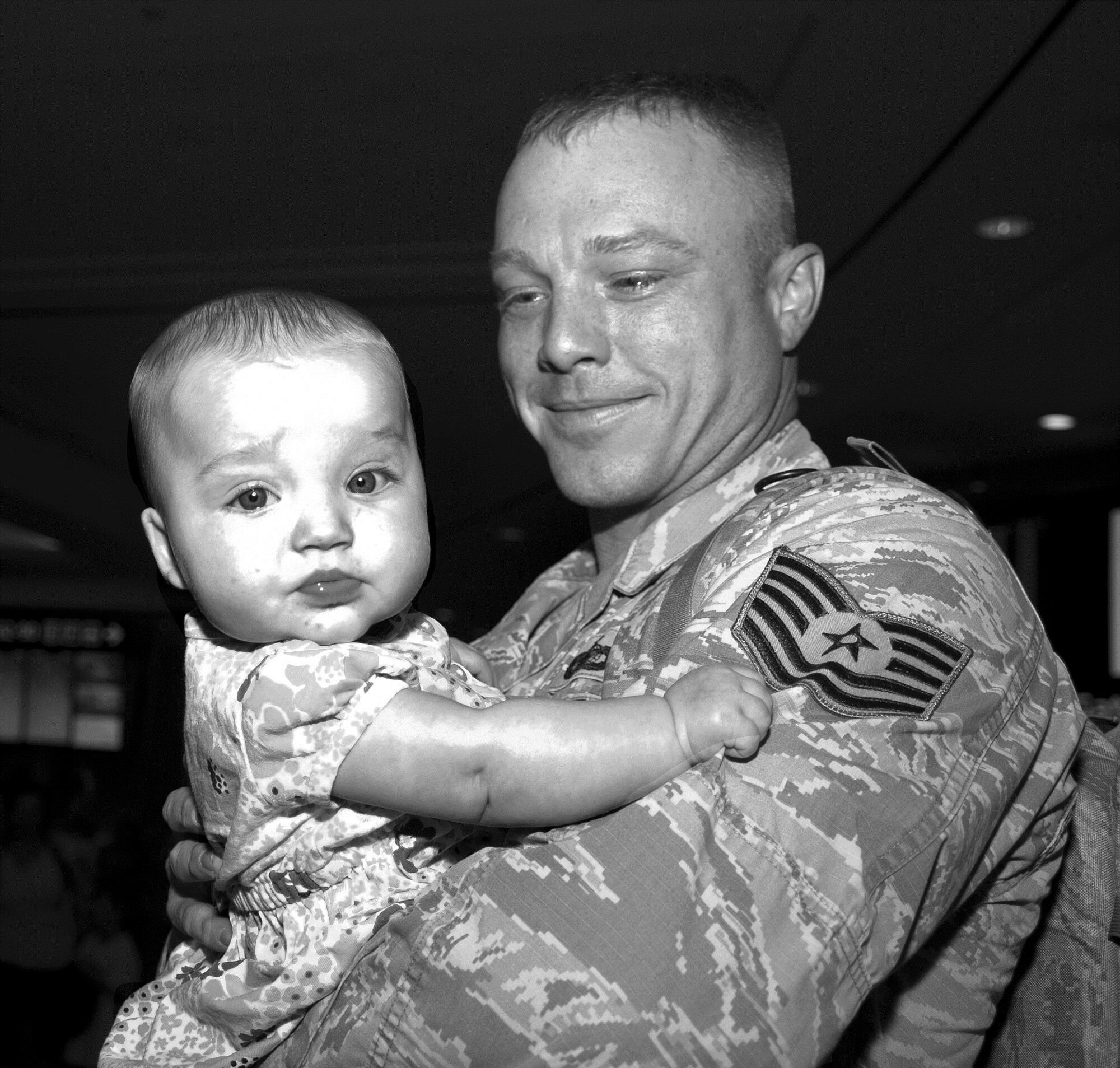 Tech. Sgt. Shannon Hutto, 6th Security Forces Squadron patrolmen holds his six-month-old daughter for the first time, Addelyn, July 21, 2015 at Tampa International Airport in Tampa, Fla. Hutto left for a seven month deployment two weeks before Addelyn’s birth. (U.S. Air Force photo by Senior Airman Jenay Randolph/Released)