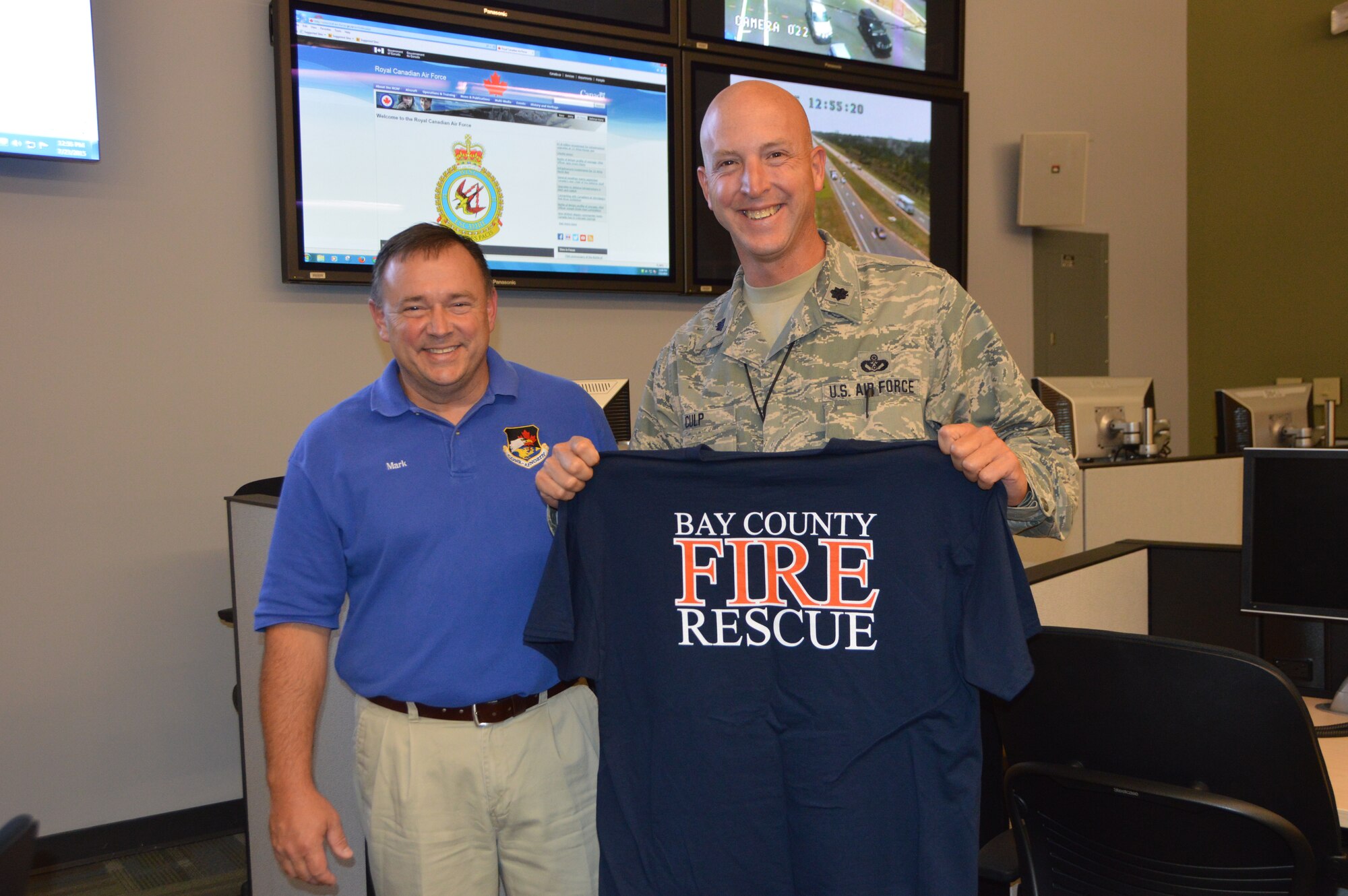 Mark Bowen, (right) Chief, Bay County Emergency Services, joins Lt. Col. James Culp, Director, Continental U.S. Aerospace Defense Command Region – 1st Air Force  (Air Forces Northern) Installations and Mission Support directorate, after Culp was presented with a Bay County Emergency Operations Center an organizational T-shirt. Culp and other members of the CONR-1st AF (AFNORTH) organization visited the Bay County EOC to learn more about how Bay County officials conduct contingency operations. (Air Force photo released/Mary McHale)