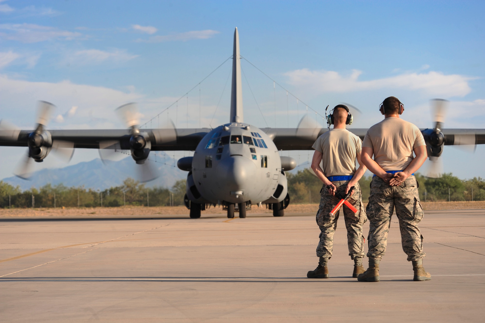 U.S. Air Force Airman 1st Class Joseph Crick, 755th Aircraft Maintenance Squadron special operations forces and personell recovery communication navigation mision system specialist, prepares to marshal an EC-130H Compass Call on the flightline while Senior Airman Nicholas Novotny, 755th AMXS crew chief supervises at Daivs-Monthan Air Force Base, Ariz., July 15, 2015. The 755th AMXS provides war-fighting commanders with combat-ready EC-130H Compass Call aircraft to expeditiously execute information warfare and electronic attack operations. The 755th AMXS plans and executes all on-equipment maintenance actions for 14 EC-130H Compass Call and 1 TC-130H Hercules aircraft. These actions include launch, recovery, scheduled inspections, servicing and component replacement. (U.S. Air Force photo by Airman 1st Class Cheyenne Morigeau/Released)