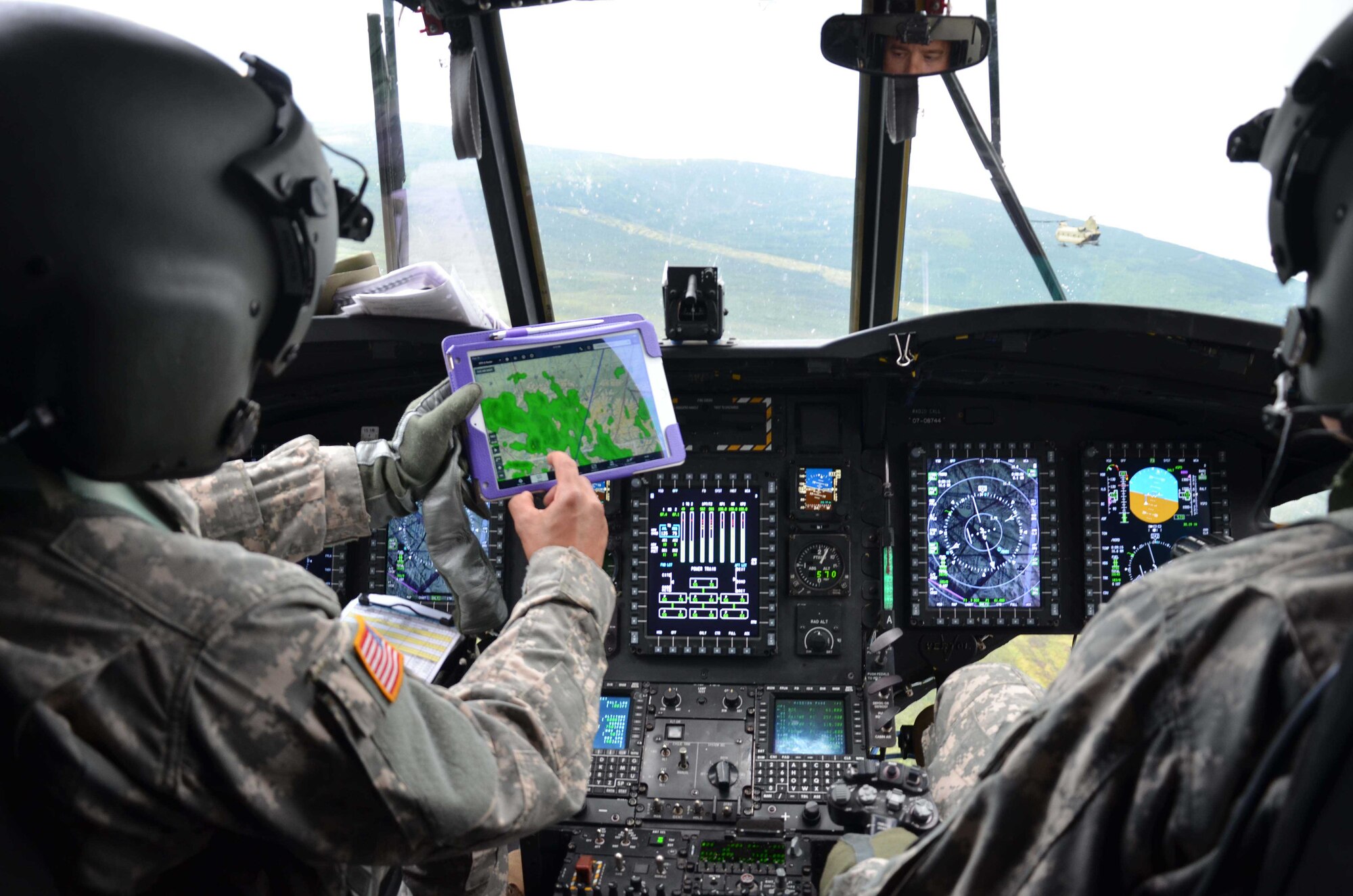 Chief Warrant Officer 3 Rafael Caldeira (left) uses a tablet to show current weather conditions to fellow pilot Chief Warrant Officer 4 Dave Lawson, as the two Soldiers fly their CH-47 Chinook from Ft. Wainwright, Alaska, 60 miles north of the Arctic Circle July 24, 2015.  The crew was part of the mission to relocate radiologic material belonging to the Air Force Technical Applications Center from Burnt Mountain to the Nevada National Security Site for permanent disposal.  (U.S. Air Force photo by Susan A. Romano)