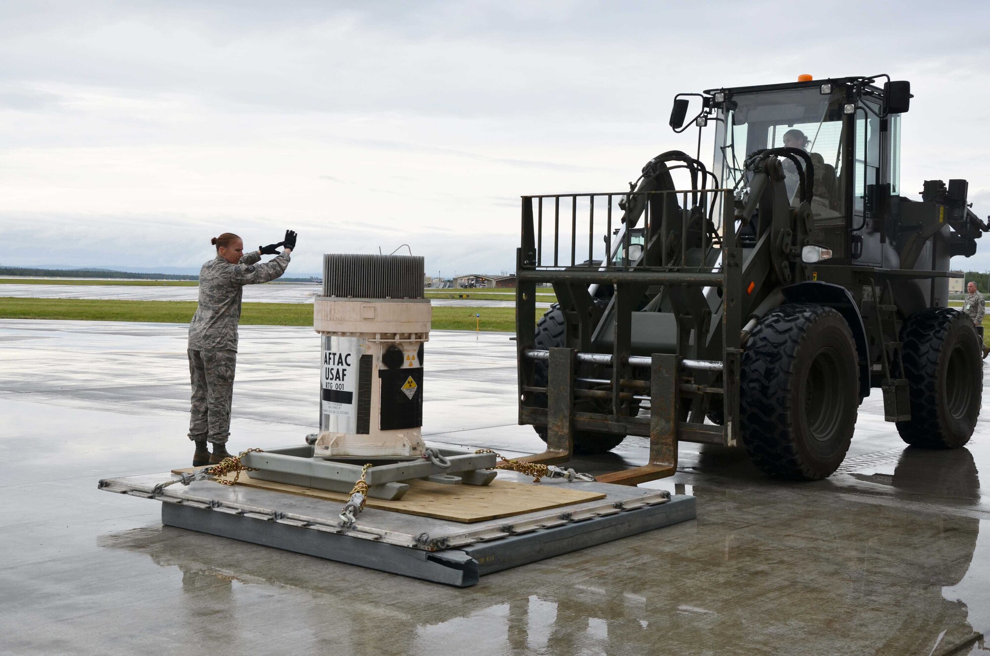 Tech. Sgt. Rebecca Morin, 354th Logistics Readiness Squadaron noncommissioned officer in charge of air terminal operations at Eielson AFB, Alaska, gives hand signals to forklift driver Staff Sgt. Rebecca Bartlett as Bartlett slowly places a pallet containing a radioisotope thermoelectric generator on the ground July 14, 2015.  Their efforts were part of the larger mission to remove the Air Force Technical Applications Center's 10 radiologic RTGs from Burnt Mountain to have them permanently disposed of at the Nevada National Security Site.  (U.S. Air Force photo by Susan A. Romano)