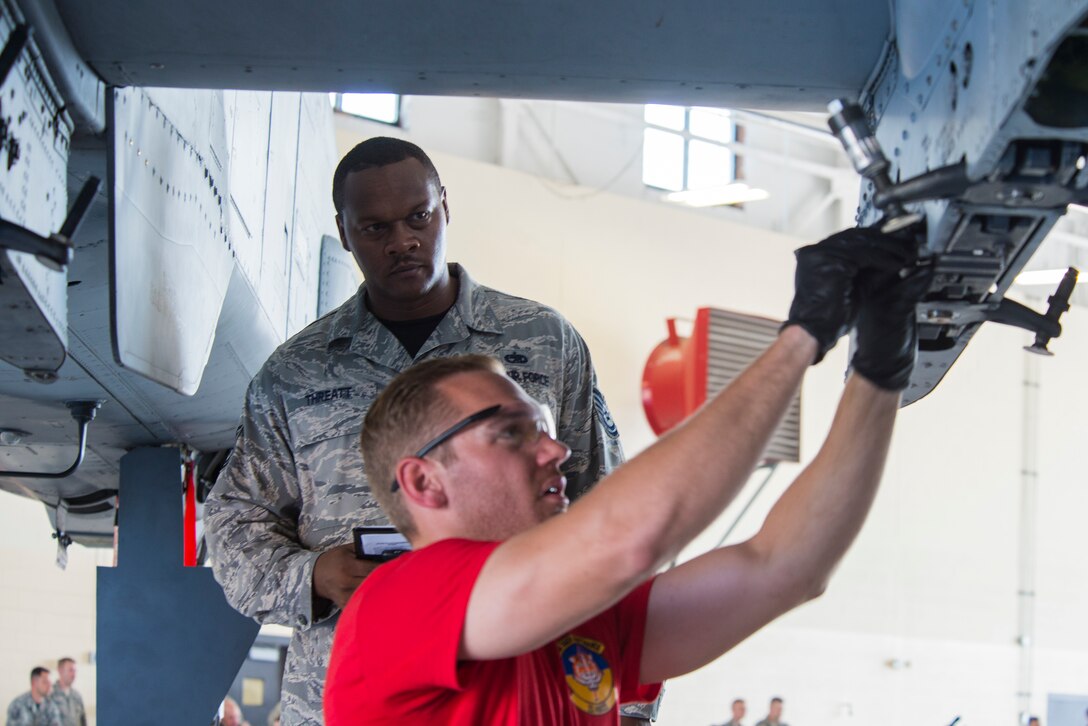 U.S. Air Force Tech. Sgt. Zedrick Threatt,  (right), 23d Maintenance Group weapons loading standardization crew member, evaluates loading procedures during the load crew of the quarter competition July 17, 2015, at Moody Air Force Base, Ga. The 23d MXG weapons standardization section judged the load crew competitors on various categories to include dress and appearance, knowledge exam, and loading munitions quickly and efficiently. (U.S. Air Force photo by Airman 1st Class Ceaira Tinsley/Released)
