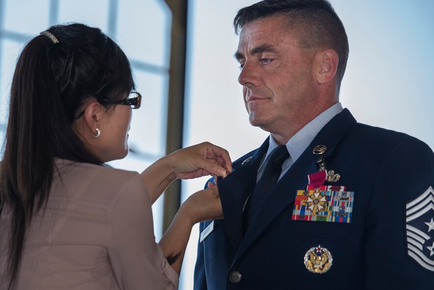 U.S. Air Force Chief Master Sgt. Charles Burgess, 82nd Training Wing command chief, receives his retirement pin from his wife, Chong Burgess, July 31, 2015, at Sheppard Air Force Base, Texas. Burgess received his pin after serving a 28-year Air Force career. (U.S. Air Force photo by Senior Airman Kyle Gese/Released)