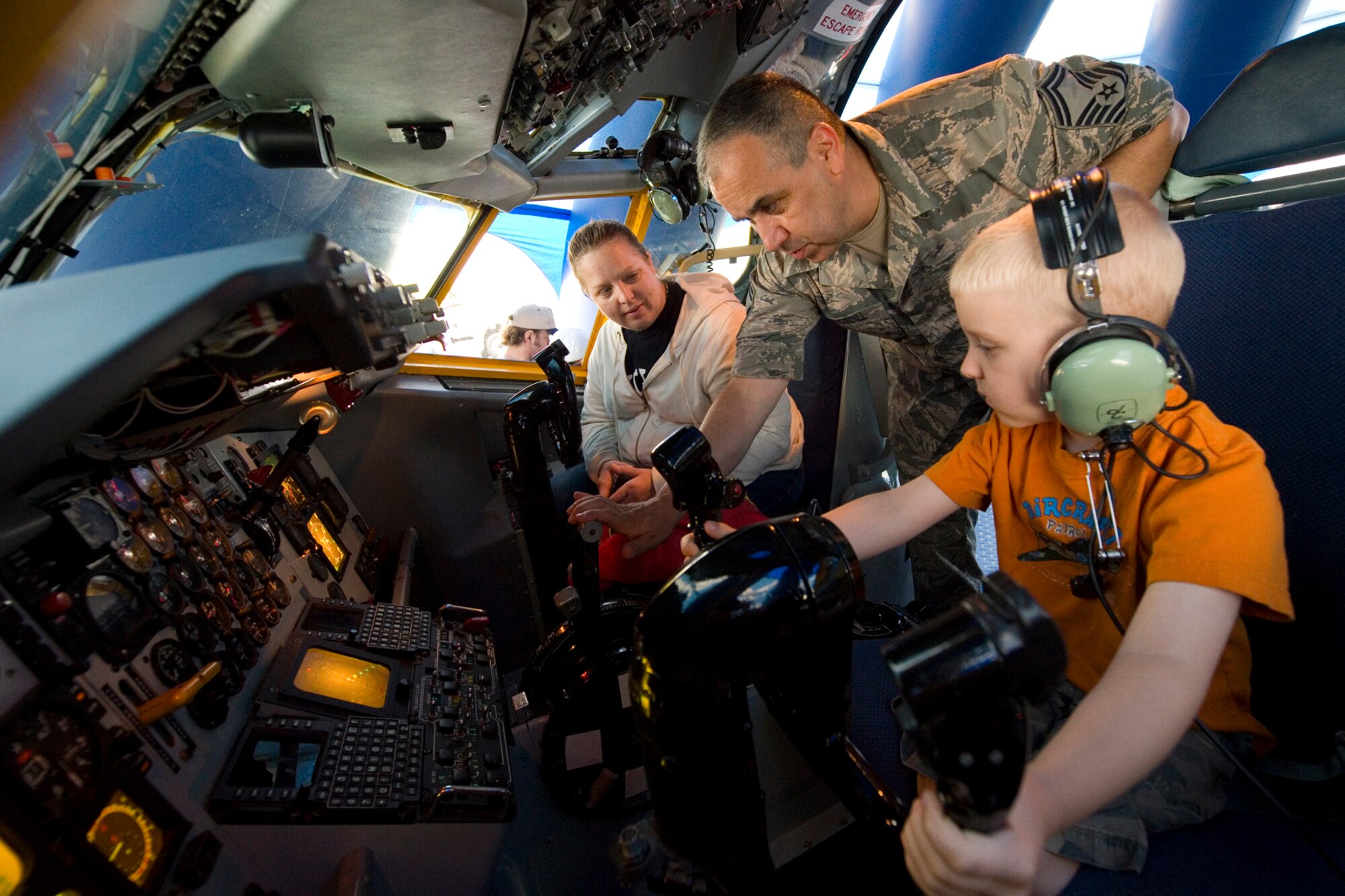 Senior Master Sgt. Douglas Stogsdill, 434th Maintenance Squadron fabrications flight chief, explains the controls of a KC-135R Stratotanker interactive flight deck to Lori Leach and her son Cooper Leach at the Dayton Vectron Airshow in Dayton, Ohio, June 20, 2015. During the event, Stogsdill and seven other Airmen volunteered to setup up and operate the displays while sharing their military knowledge with visitors. (U.S. Air Force photo/Tech. Sgt. Benjamin Mota)