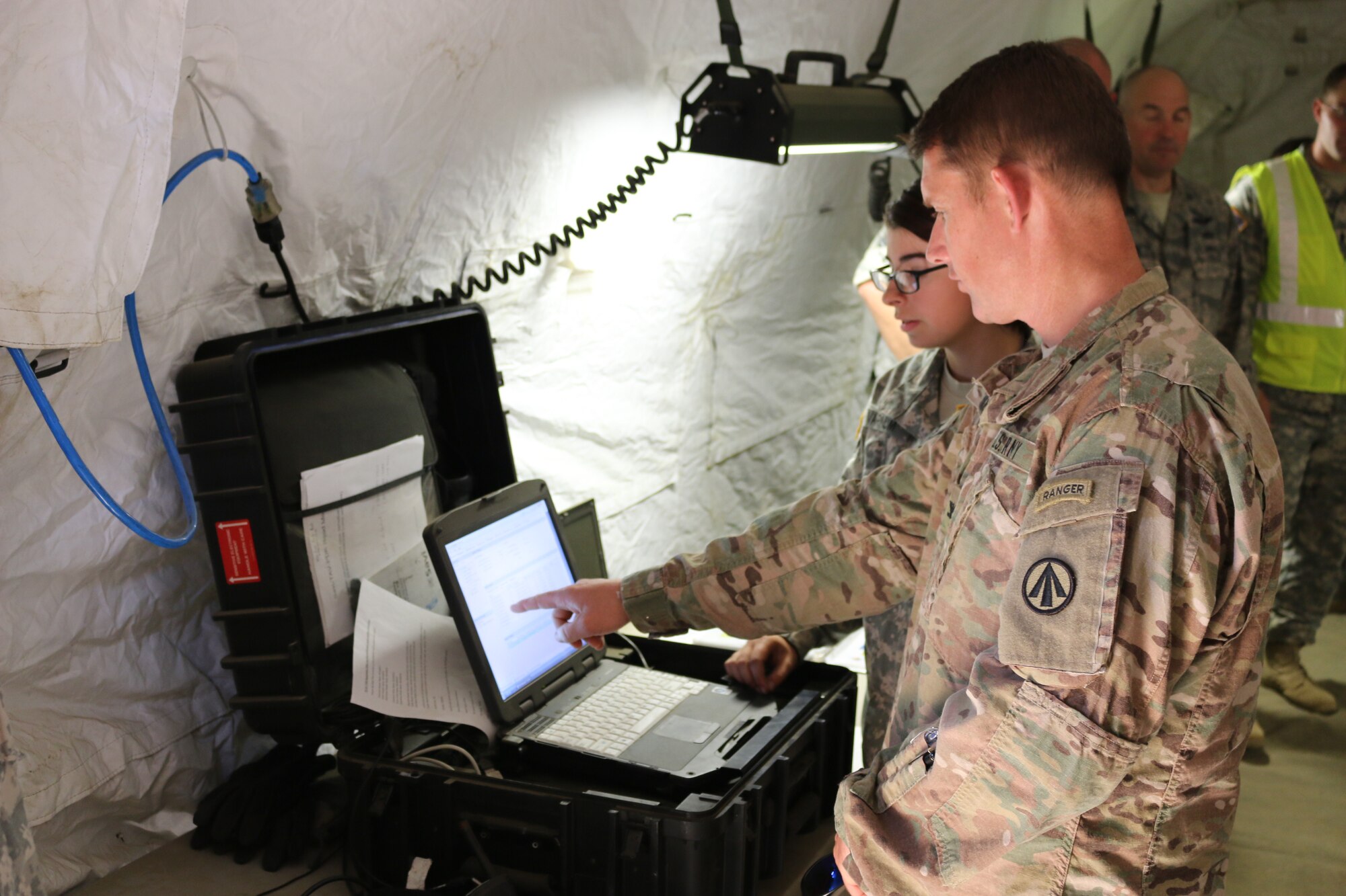 Col. Stephen Riley, 597th Transportation Brigade commander, receives a status briefing from a 690th Rapid Port Opening Element Soldier at the forward node during the closing day of Exercise Turbo Distribution 15-7 at Joint Base McGuire-Dix-Lakehurst, N.J., July 24, 2015.. (U.S. Army photo by Loran Doane/Released)