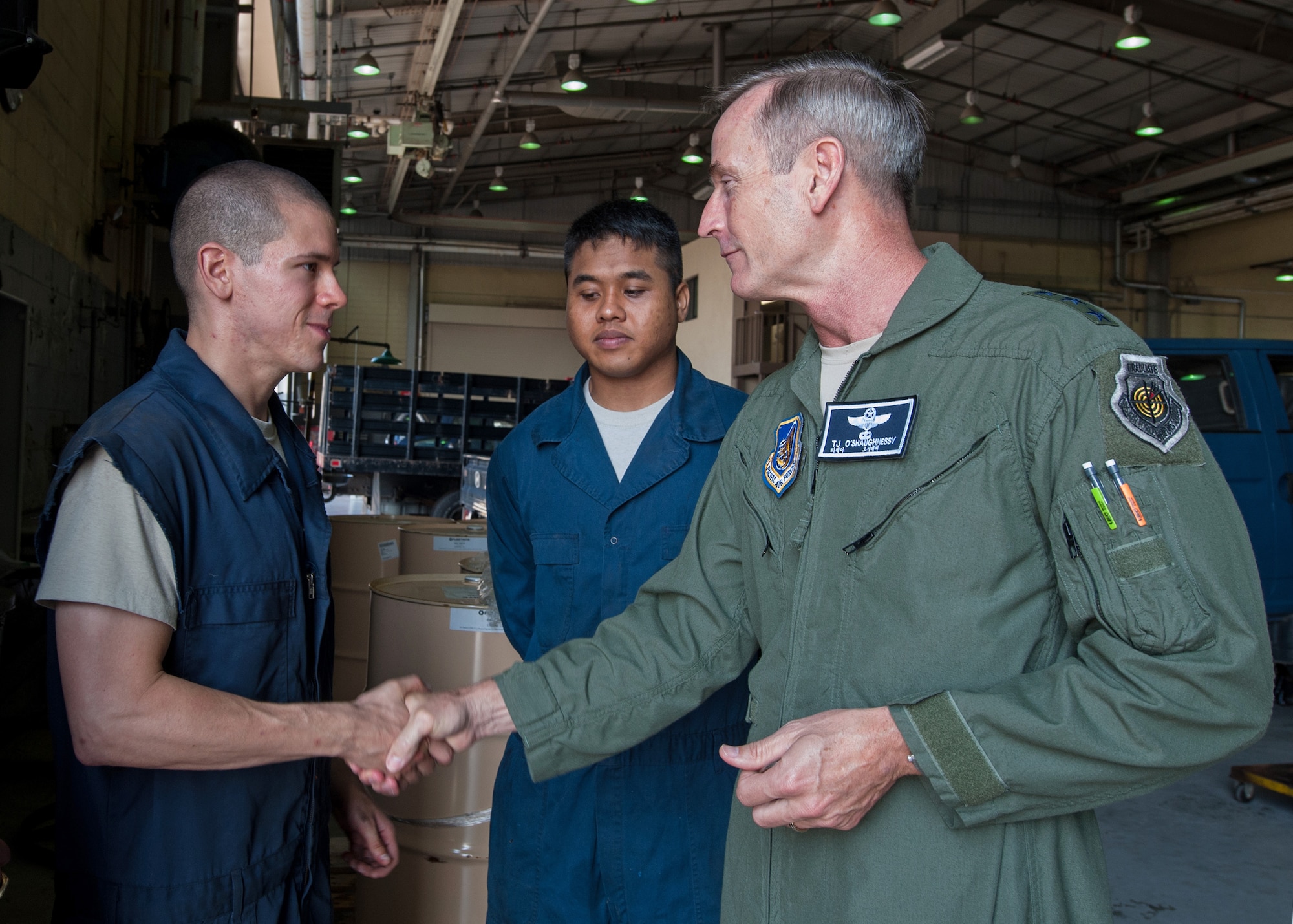 Lt. Gen. Terrence O'Shaughnessy, 7th Air Force and Air Component Command U.S. Forces Korea/U.S. Combined Forces commander, coins Senior Airman Peter Hernandez, 8th Logistics Readiness Squadron general purpose vehicle mechanic, as Senior Airman Evin Diaz, 8th LRS general vehicle mechanic, looks on, at Kunsan Air Base, Republic of Korea, July 31, 2015. During O’Shaughnessy’s two-day visit, he saw first-hand how the Wolf Pack contributes to deterring aggression on the peninsula. (U.S. Air Force photo by Senior Airman Katrina Heikkinen/Released)