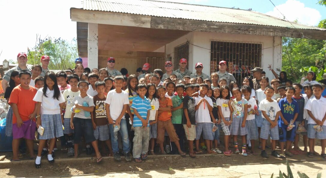 Airmen assigned to the 554th Red Horse Squadron stand with school children from San Remigio Elementary School July 22, 2015, in Cebu Province, Philippines. U.S. and Philippine service members came together for a joint exchange project to construct a two-classroom school building and provide repairs at San Remigio Central Elementary School. (U.S. Army photo by Staff Sgt. Jim Evangelista/Released)