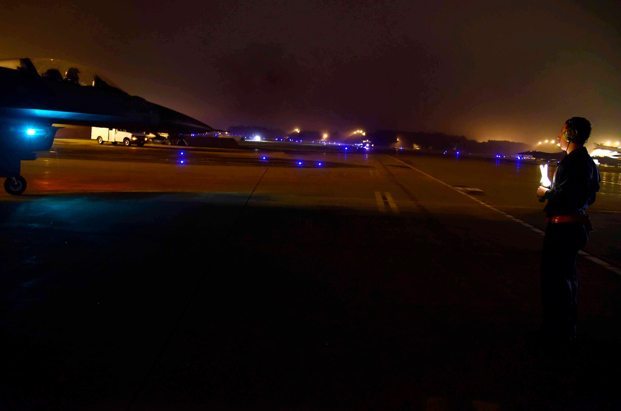U.S. Air Force Airman 1st Class Jose Rosales, 35th Aircraft Maintenance Squadron assistant dedicated crew chief, marshals an F-16 Fighting Falcon at Misawa Air Base, Japan, July 28, 2015. Night operations require crew chiefs to have additional safety equipment including light wands, reflective belts and flashlights, to ensure aircraft are ready to fly. (U.S. Air Force photo by Airman 1st Class Jordyn Fetter/Released)