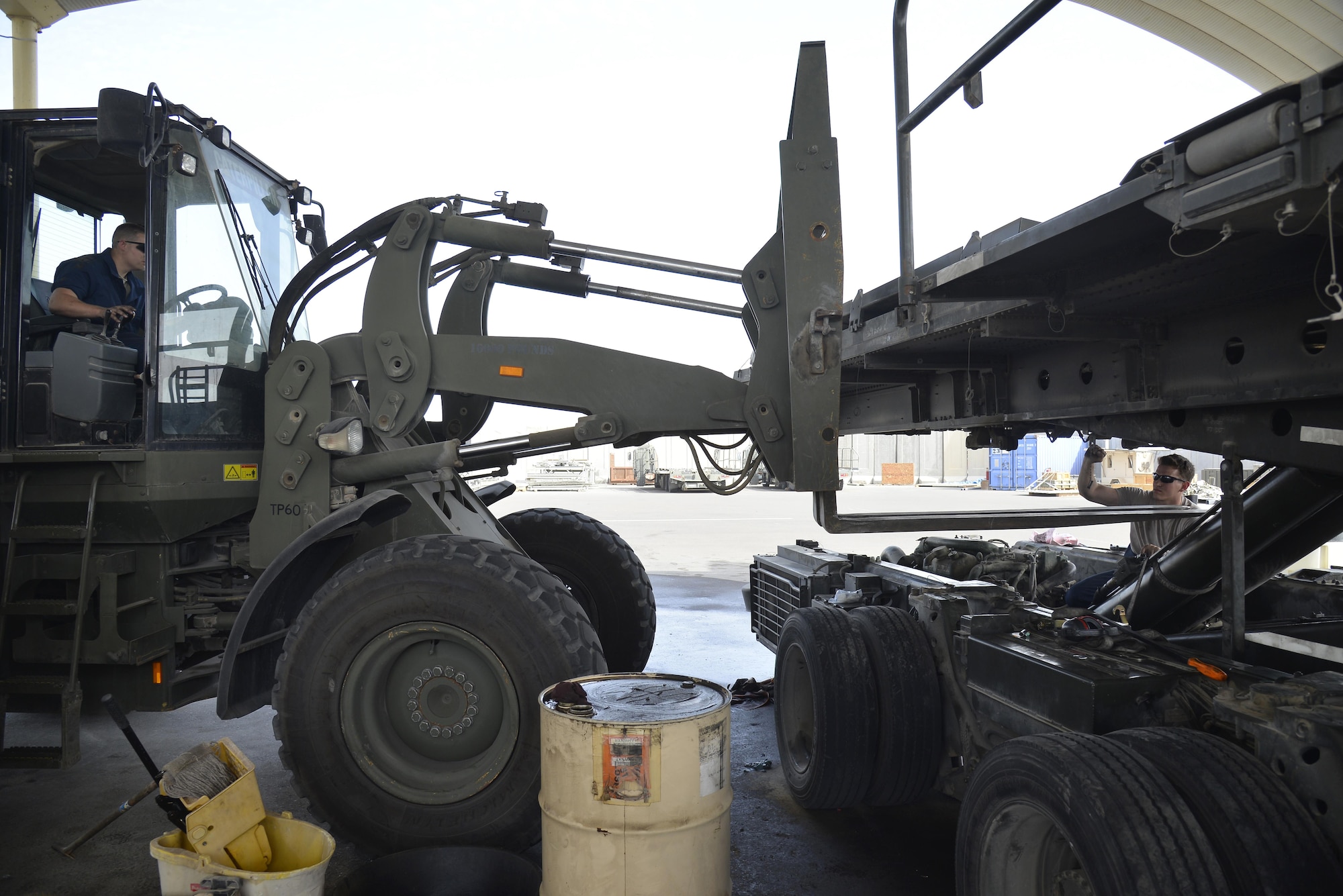 Staff Sgt. Jason, left, and Senior Airman Jacob, right, position an adverse terrain forklift vehicle underneath a 60K aircraft loader during maintenance at an undisclosed location in Southwest Asia May 24, 2015. The forklift was used to relieve weight off of the lift cylinder. Jason is the noncommissioned officer in charge of material handling equipment and Jacob is a MHE mechanic. Both are assigned to the Expeditionary Logistics Readiness Squadron. Due to safety and security reasons, last names and unit designators were removed. (U.S. Air Force photo/Tech. Sgt. Christopher Boitz) 