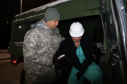 Army Staff Sgt. Gerard Brown, a readiness noncommissioned officer with the Georgia Army National Guard, helps Angela Morgan, a registered nurse in Grady Memorial Hospital’s labor and delivery department, into a National Guard high mobility multipurpose wheeled vehicle, also known as HUMVEE. Brown is part of the National Guard teams working to help transport snowbound Grady staff to the hospital.