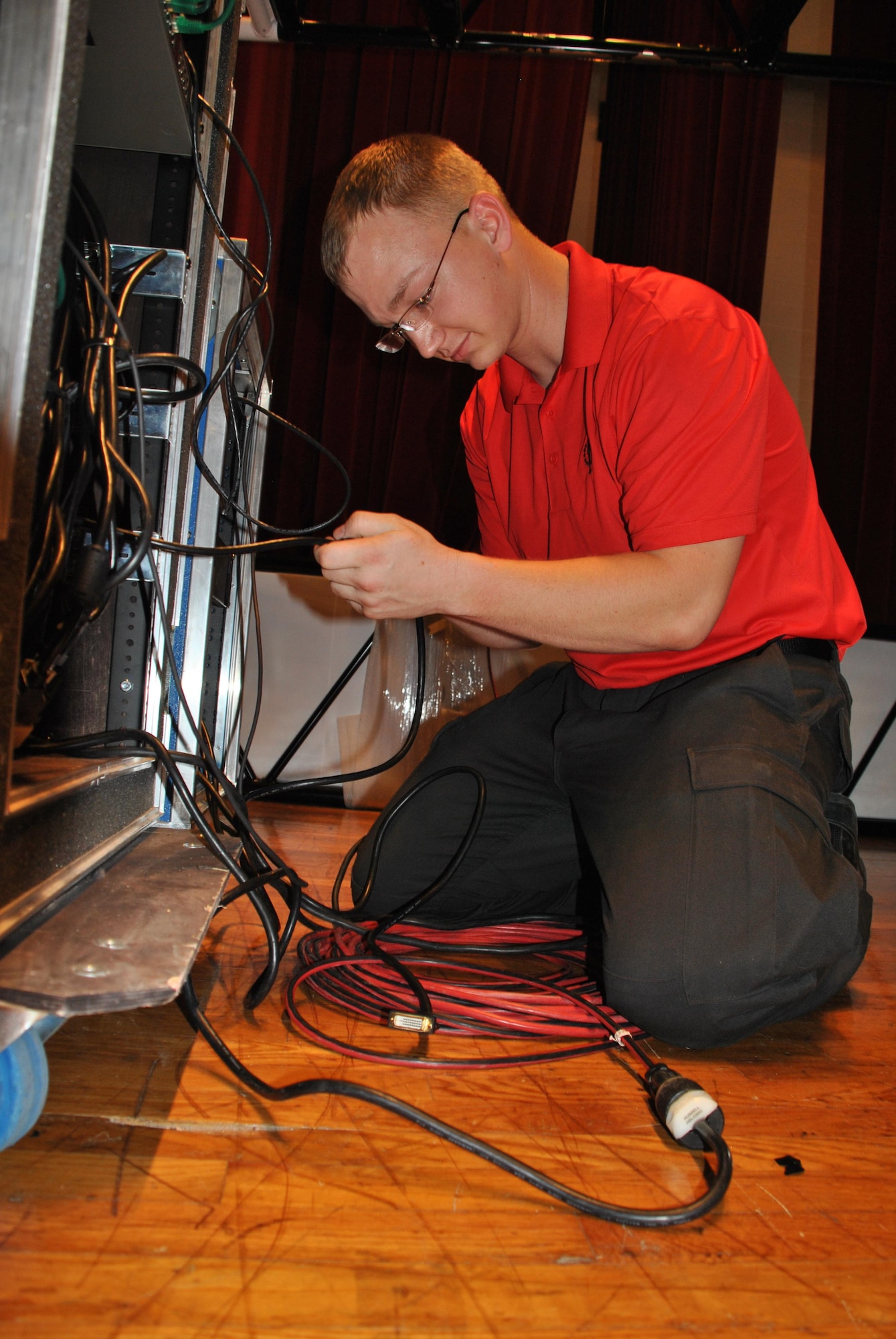 Senior Airman Christopher Hayes, video director for Tops In Blue, connects equipment to test a video presentation at the Joint Base San Antonio-Lackland Bob Hope Theater, May 11. Hayes and the rest of the TIB Technical Flight are excited to begin the 2015 tour next week. (U.S. Air Force photo/Debbie Aragon/Released)