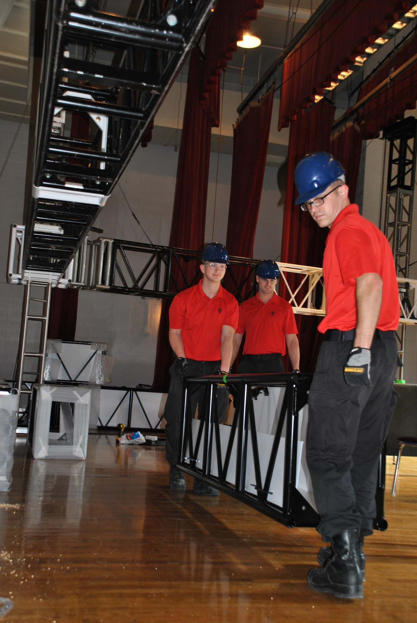 From left, Senior Airman Christopher Hayes, 1st Lt. Ethan Frazier and Senior Airman Mason Hack position a newly powder-coated piece of staging at the Joint Base San Antonio-Lackland Bob Hope theater, May 11. The Tops in Blue Technical Flight consists of a technical director, two vehicle operators, a video director, lighting director, audio director and audio engineer. (U.S. Air Force photo/Debbie Aragon/Released)
