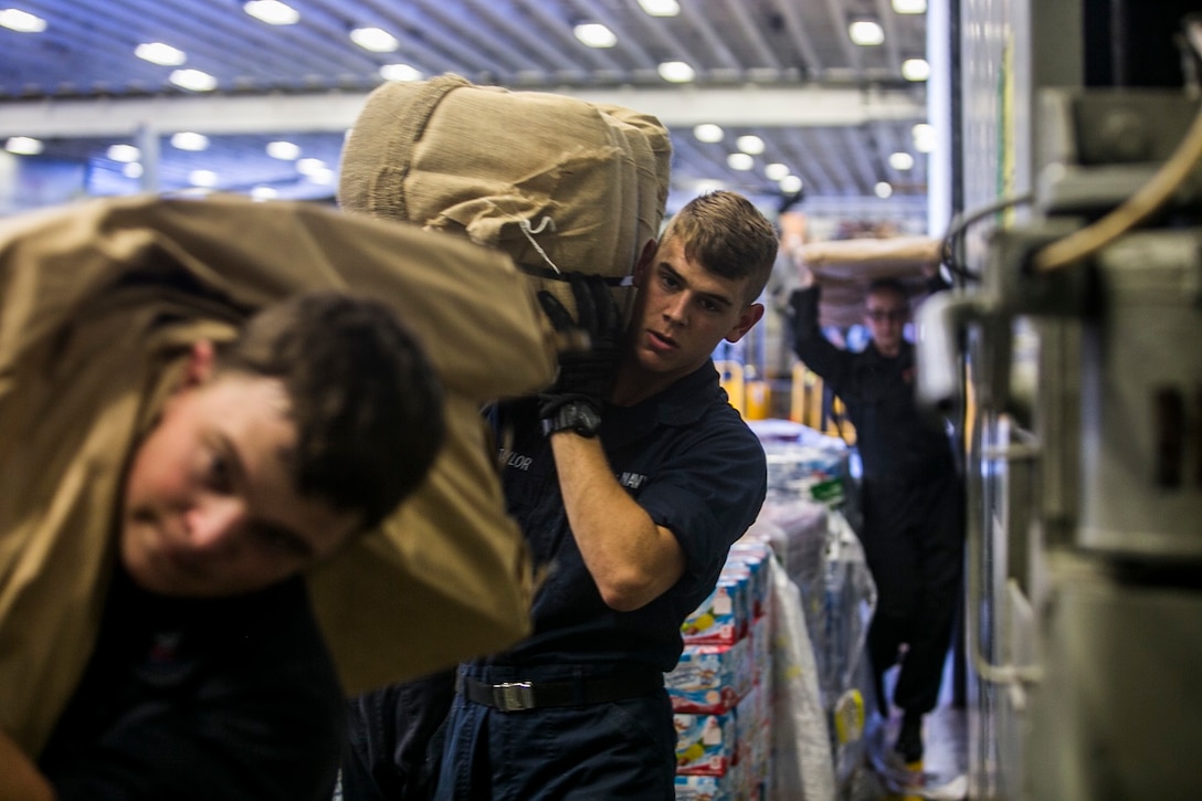 U.S. Sailors with the Essex Amphibious Ready Group carry mail and food through the ship during replenishment at sea aboard the USS Essex (LHD 2) in the Pacific Ocean, May 31, 2015. The USS Essex replenishes at sea in order to continue its mission without stopping forward progress. (U.S. Marine Corps photo by Cpl. Anna Albrecht/Released)