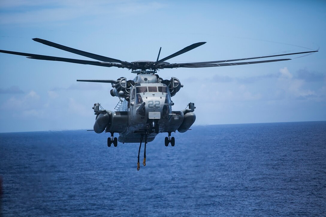 A CH-53E Super Stallion with Medium Marine Tiltrotor Squadron 161 (Reinforced), 15th Marine Expeditionary Unit, prepares to lift an AV-8B Harrier engine off the flight deck of the USS Essex (LHD 2) at sea in the Pacific Ocean, May 31, 2015. The engine was transported to the USNS Wally Schirra (T-AKE 8) during a replenishment at sea. (U.S. Marine Corps photo by Cpl. Anna Albrecht/Released)