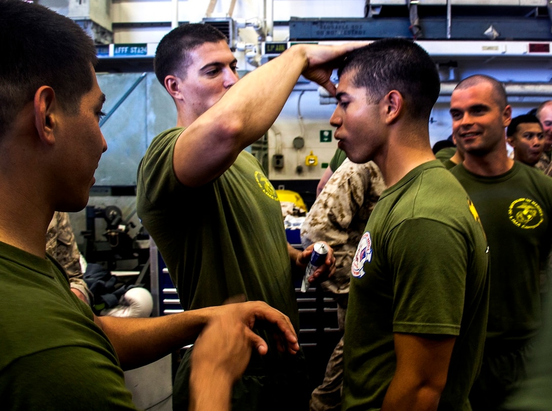 U.S. Marine Cpl. Roman Fernandez, right, gets Vaseline applied to his face to compensate for glove friction in the hangar bay of the USS Essex (LHD 2) at sea in the Pacific Ocean, May 29, 2015. Fernandez is a team leader with Lima Company, Battalion Landing Team 3rd Battalion, 1st Marine Regiment, 15th Marine Expeditionary Unit. The Marines find unique ways to continue to maintain combat readiness during their seven-month deployment through the Pacific and Central Command areas. (U.S. Marine Corps photo by Cpl. Elize McKelvey/released)