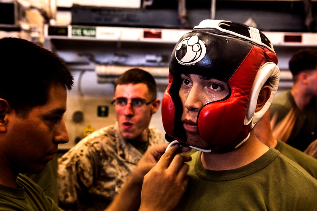 U.S. Marine Cpl. Roman Fernandez gets his gear adjusted between matches in the hangar bay of the USS Essex (LHD 2) at sea in the Pacific Ocean, May 29, 2015. Fernandez is a team leader with Lima Company, Battalion Landing Team 3rd Battalion, 1st Marine Regiment, 15th Marine Expeditionary Unit. The Marines find unique ways to continue to maintain combat readiness during their seven-month deployment through the Pacific and Central Command areas. (U.S. Marine Corps photo by Cpl. Elize McKelvey/released)