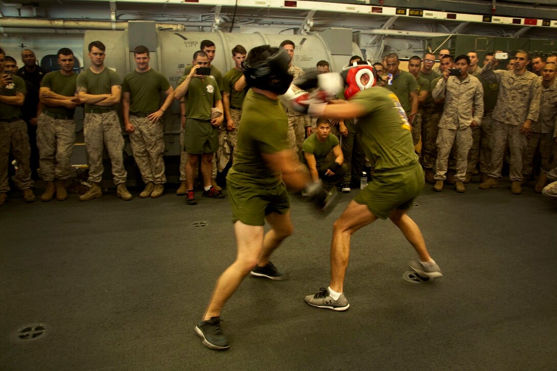 U.S. Marine Cpl. Roman Fernandez, right, and 1st Lt. Paul Hollwedel  show their speed during a boxing match in hangar bay of the USS Essex (LHD 2) at sea in the Pacific Ocean, May 29, 2015. Fernandez is a team leader and Hollwedel is the executive officer with Lima Company, Battalion Landing Team 3rd Battalion, 1st Marine Regiment, 15th Marine Expeditionary Unit. The Marines find unique ways to continue to maintain combat readiness during their seven-month deployment through the Pacific and Central Command areas. (U.S. Marine Corps photo by Cpl. Elize McKelvey/released)