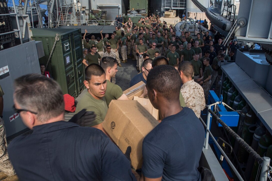 U.S. Marines and Sailors with the 15th Marine Expeditionary Unit and the Essex Amphibious Ready Group assist with an offloading packages during replenishment at sea aboard the USS Rushmore (LSD 47) at sea in the Pacific Ocean, May 31, 2015. Marines and Sailors worked together to off load supplies and mail from loved ones. (U.S. Marine Corps photo by Sgt. Emmanuel Ramos/Released)