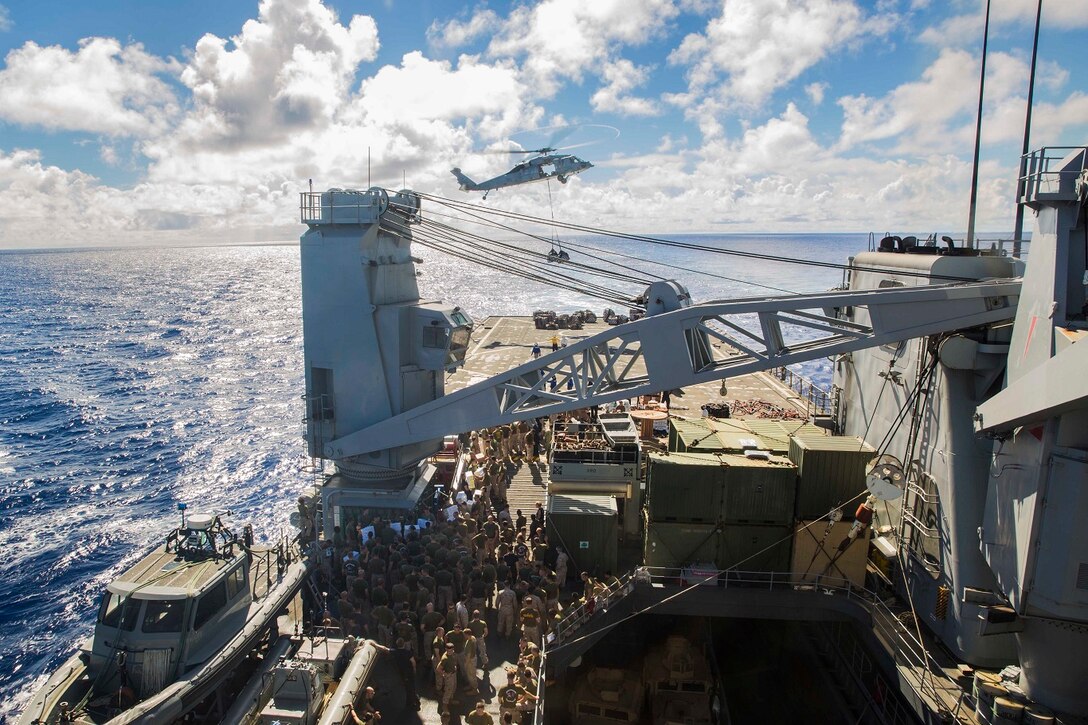 U.S. Marines and Sailors with the 15th Marine Expeditionary Unit and the Essex Amphibious Ready Group prepare to receive supplies during replenishment at sea aboard the USS Rushmore (LSD 47) at sea in the Pacific Ocean, May 31, 2015. Marines and Sailors worked together to off load supplies and mail from loved ones. (U.S. Marine Corps photo by Sgt. Emmanuel Ramos/Released)